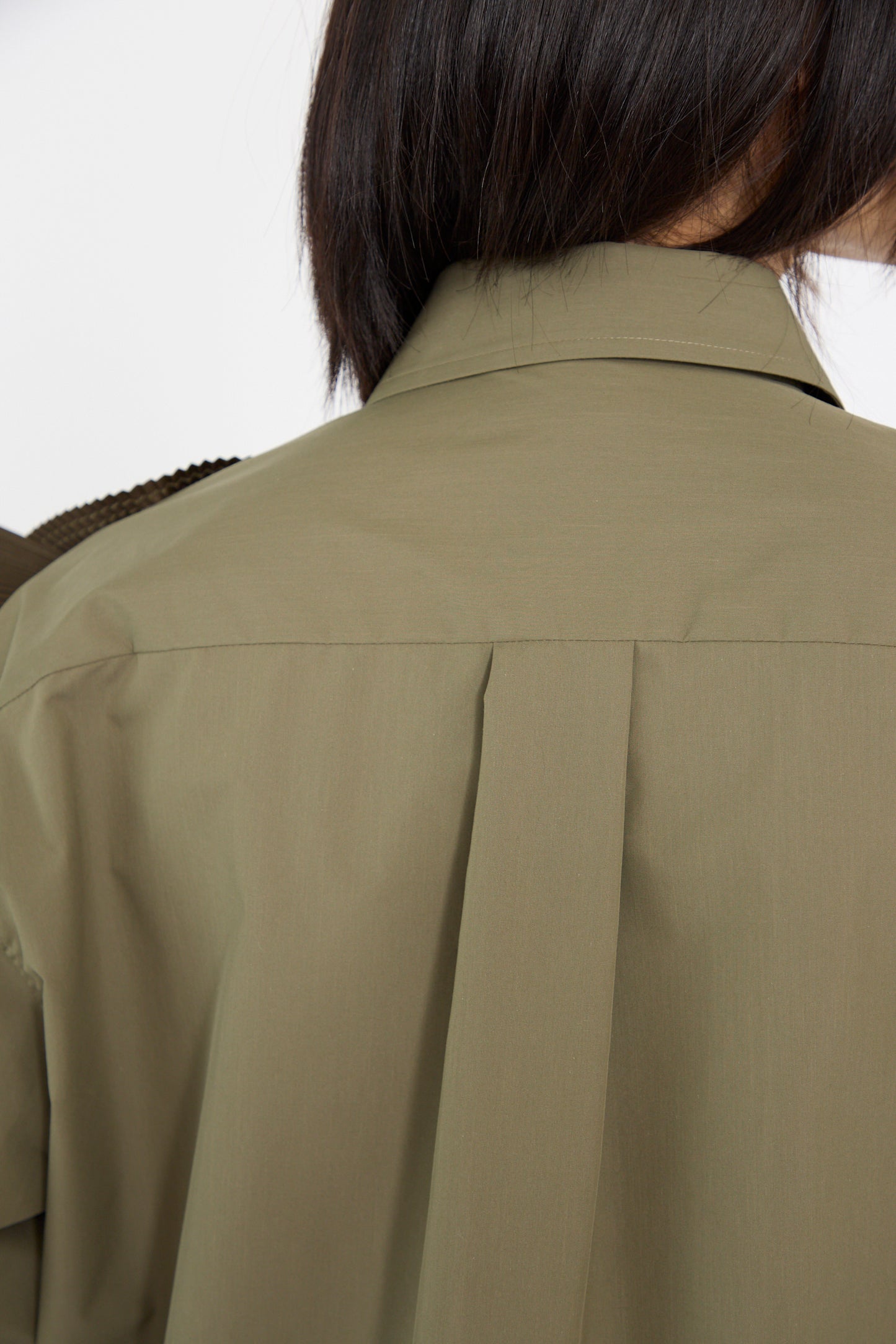 A close up of a person faced away wearing the Flower Motif Shirt in Khaki by TOGA ARCHIVES, featuring a relaxed fit and pleat detail under the collar, against a white background.