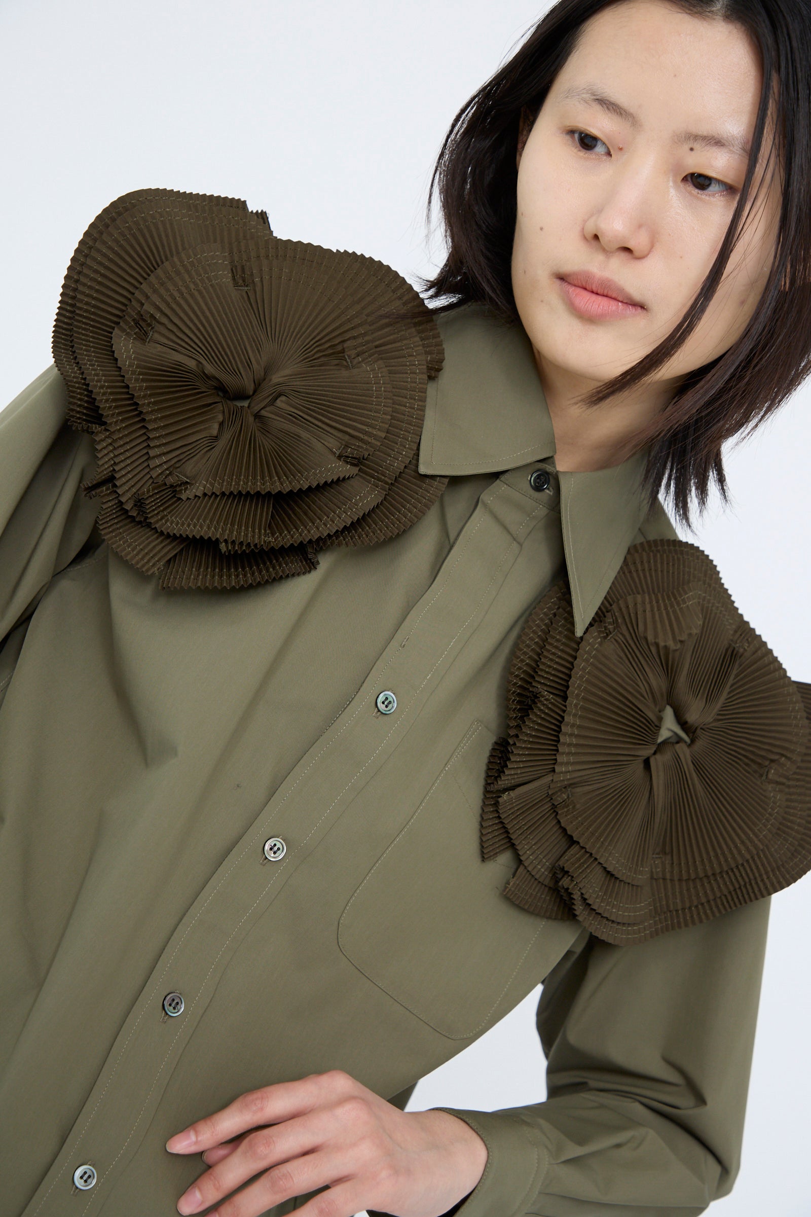 The Flower Motif Shirt in Khaki by TOGA ARCHIVES is a relaxed-fit cotton blend featuring large pleated dark brown floral accents on the shoulders, seen against a white background. 