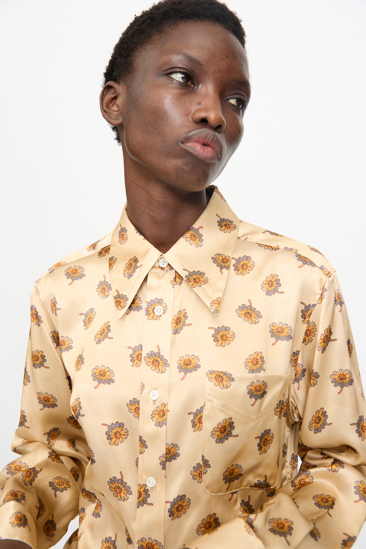 A person wears the TOGA ARCHIVES Flower Print Shirt in Beige, looking slightly to the side against a plain light background.