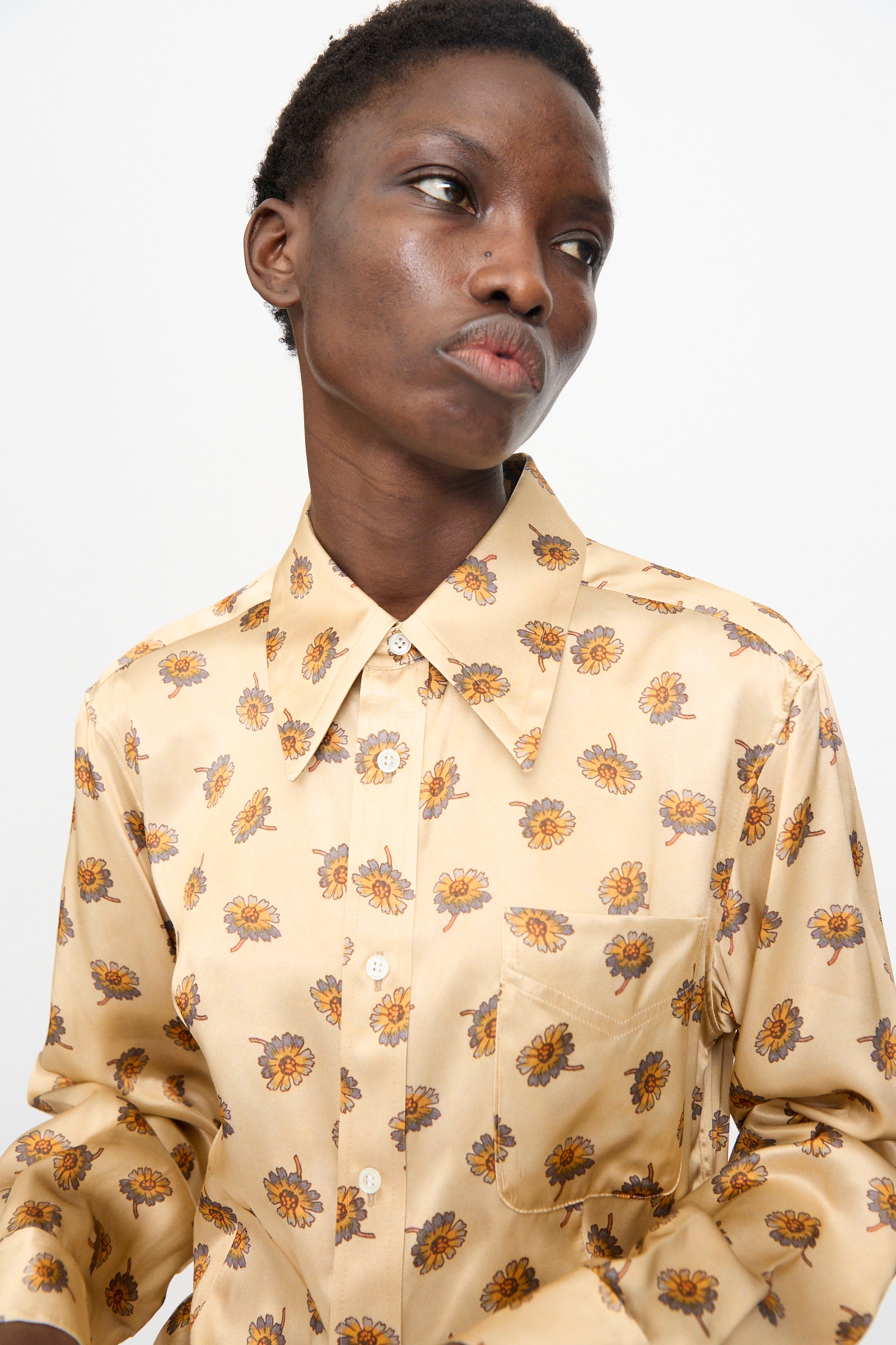 A person wears the TOGA ARCHIVES Flower Print Shirt in Beige, looking slightly to the side against a plain light background.