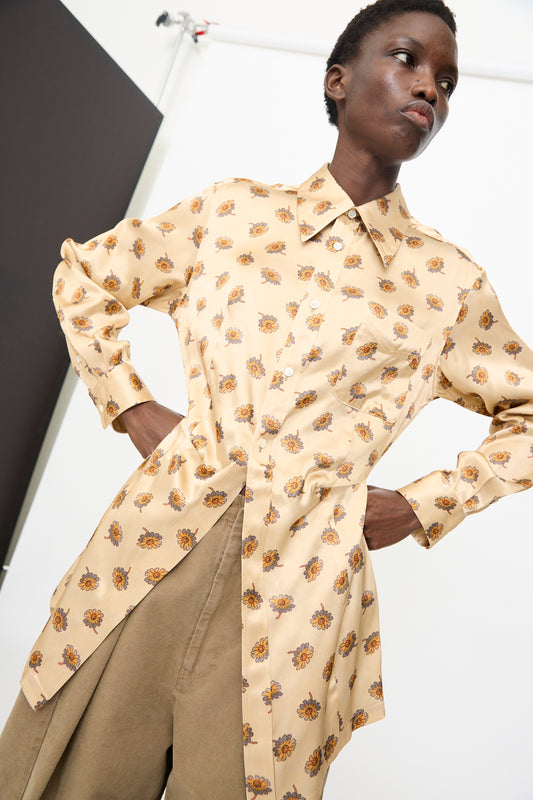 Wearing the Flower Print Shirt in Beige by TOGA ARCHIVES, a person stands with hands on hips in light brown pants against a plain indoor backdrop.