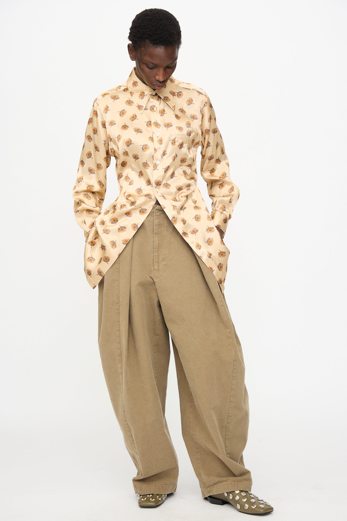 A person wears the TOGA ARCHIVES Flower Print Shirt in Beige and loose khaki pants, standing with hands in pockets against a white background. The shirt is made in Japan, ensuring premium quality and comfort.
