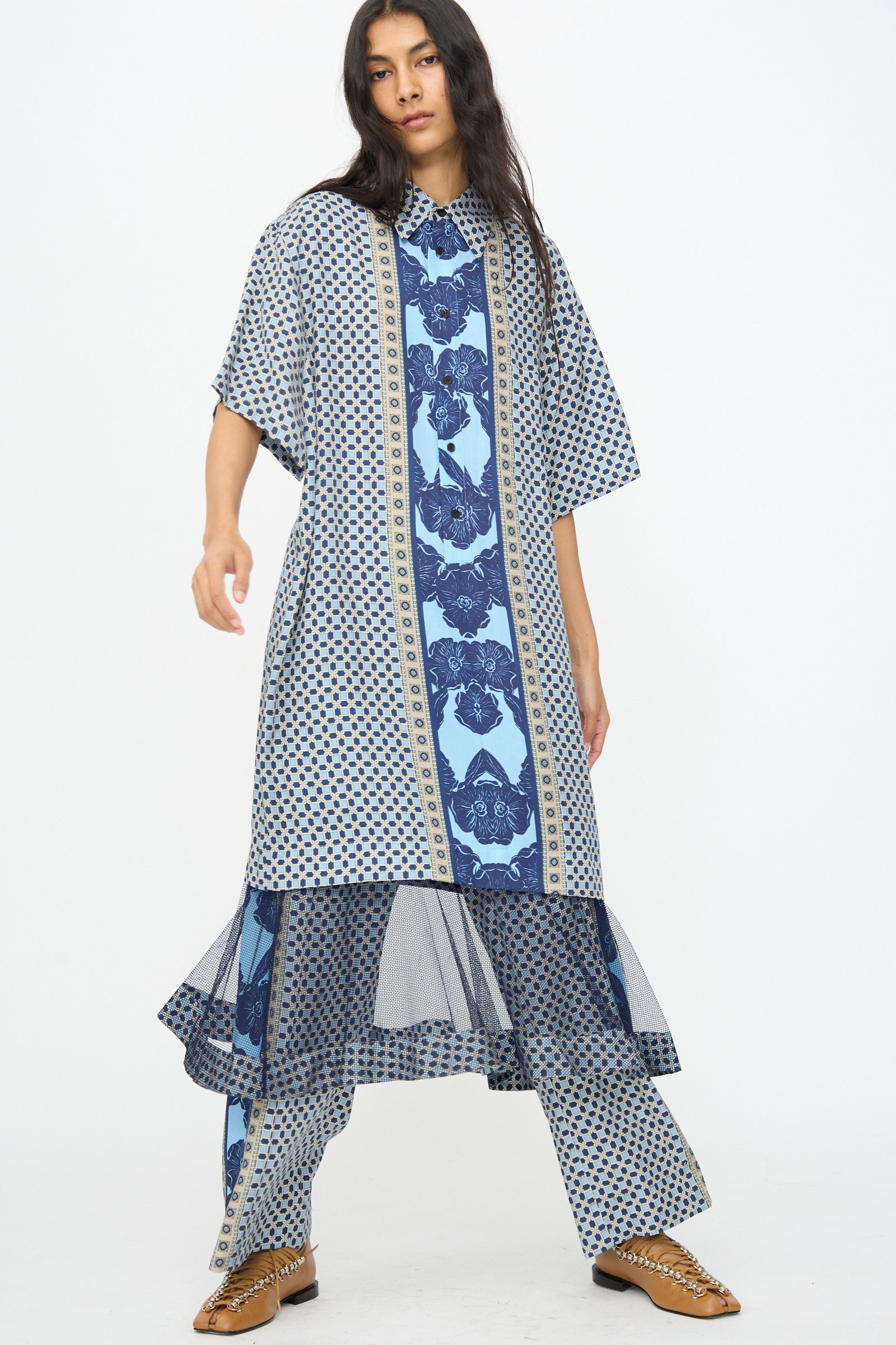 A person wears the TOGA ARCHIVES Inner Print Dress in Light Blue with matching wide-leg pants and brown shoes, standing against a plain white background.