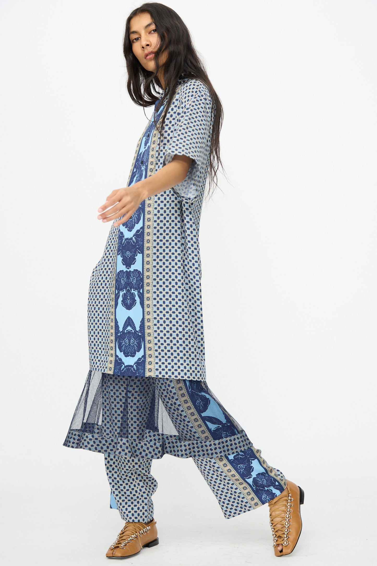 A woman wears the TOGA ARCHIVES Inner Print Dress in Light Blue, paired with matching wide-leg pants and tan woven shoes, posing against a plain white background.