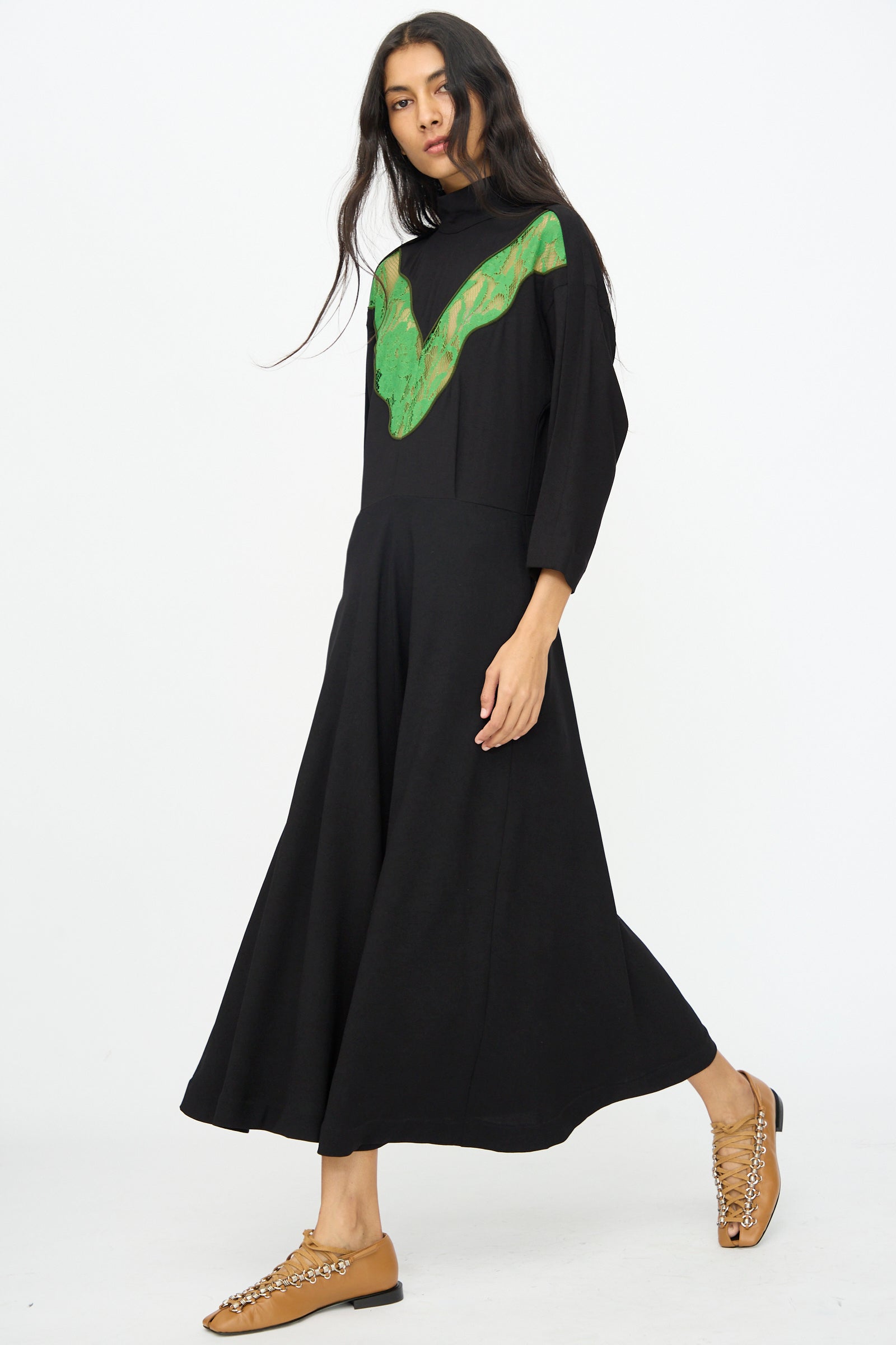 A woman wearing the TOGA ARCHIVES Lace Dress in Black stands against a plain white background.