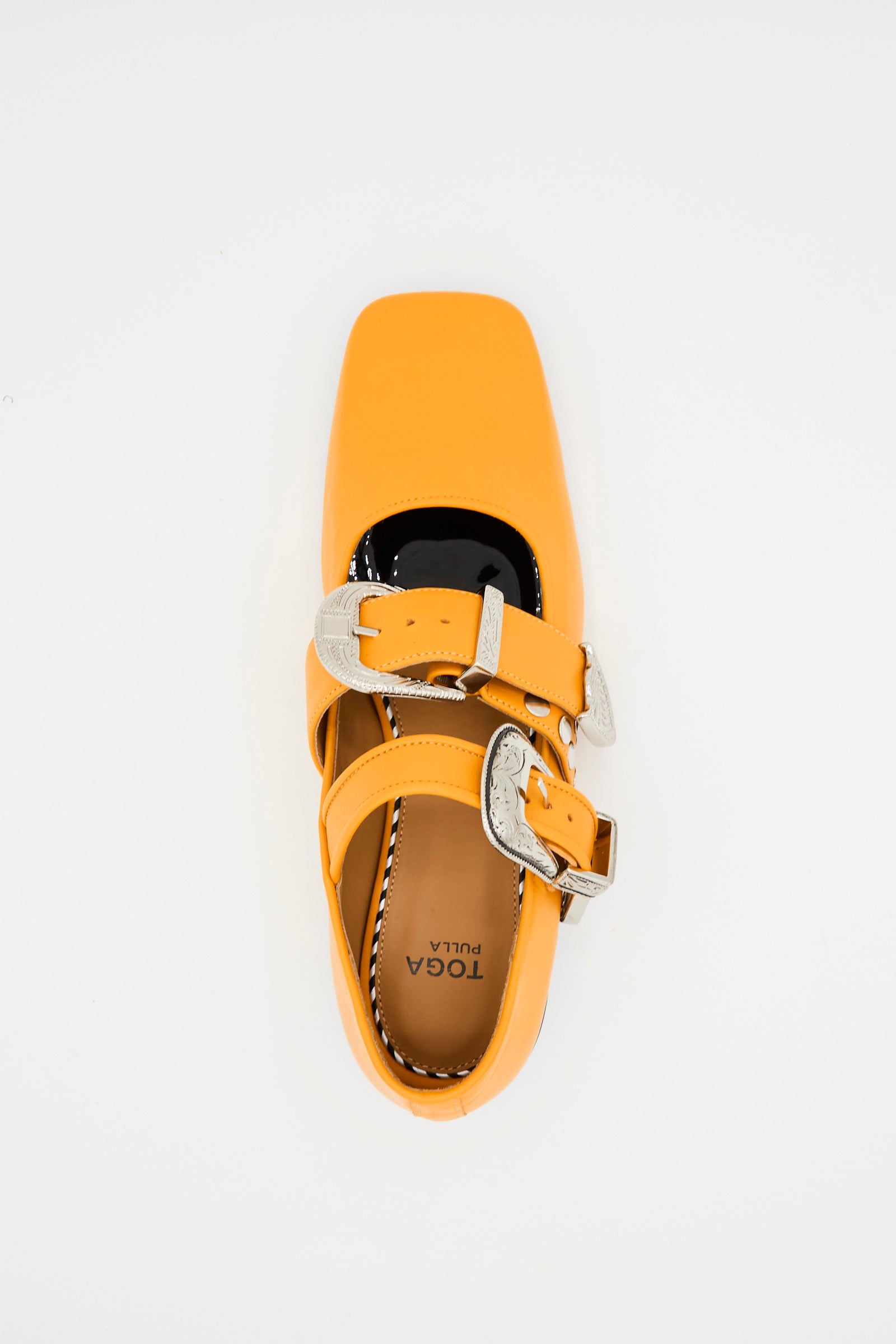 An orange leather square-toed flat with two silver pin-buckle straps, viewed from above. The insole features the "TOGA ARCHIVES" brand. Product name: Leather Flat in Orange.