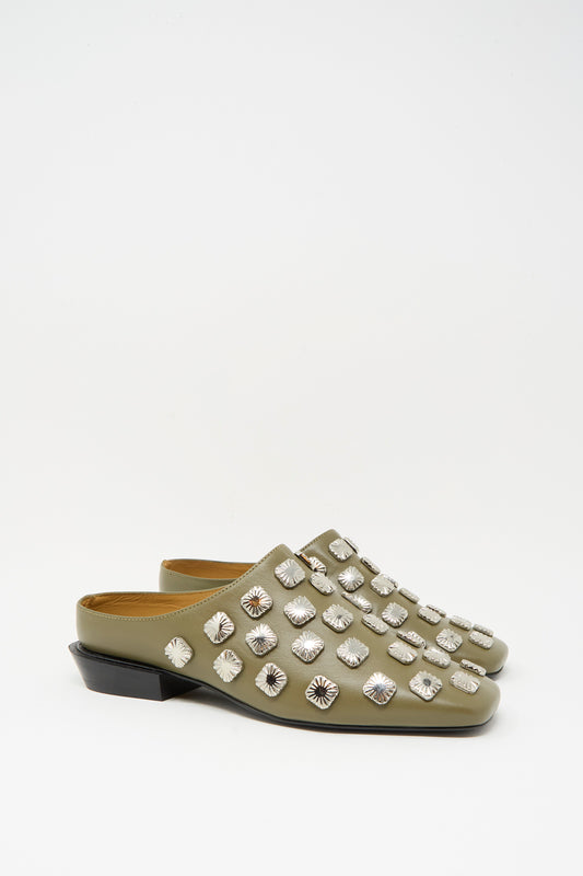 The TOGA ARCHIVES Leather Mule in Khaki features olive green leather, silver square studs, a square toe, and low black heels, shown against a plain white background.