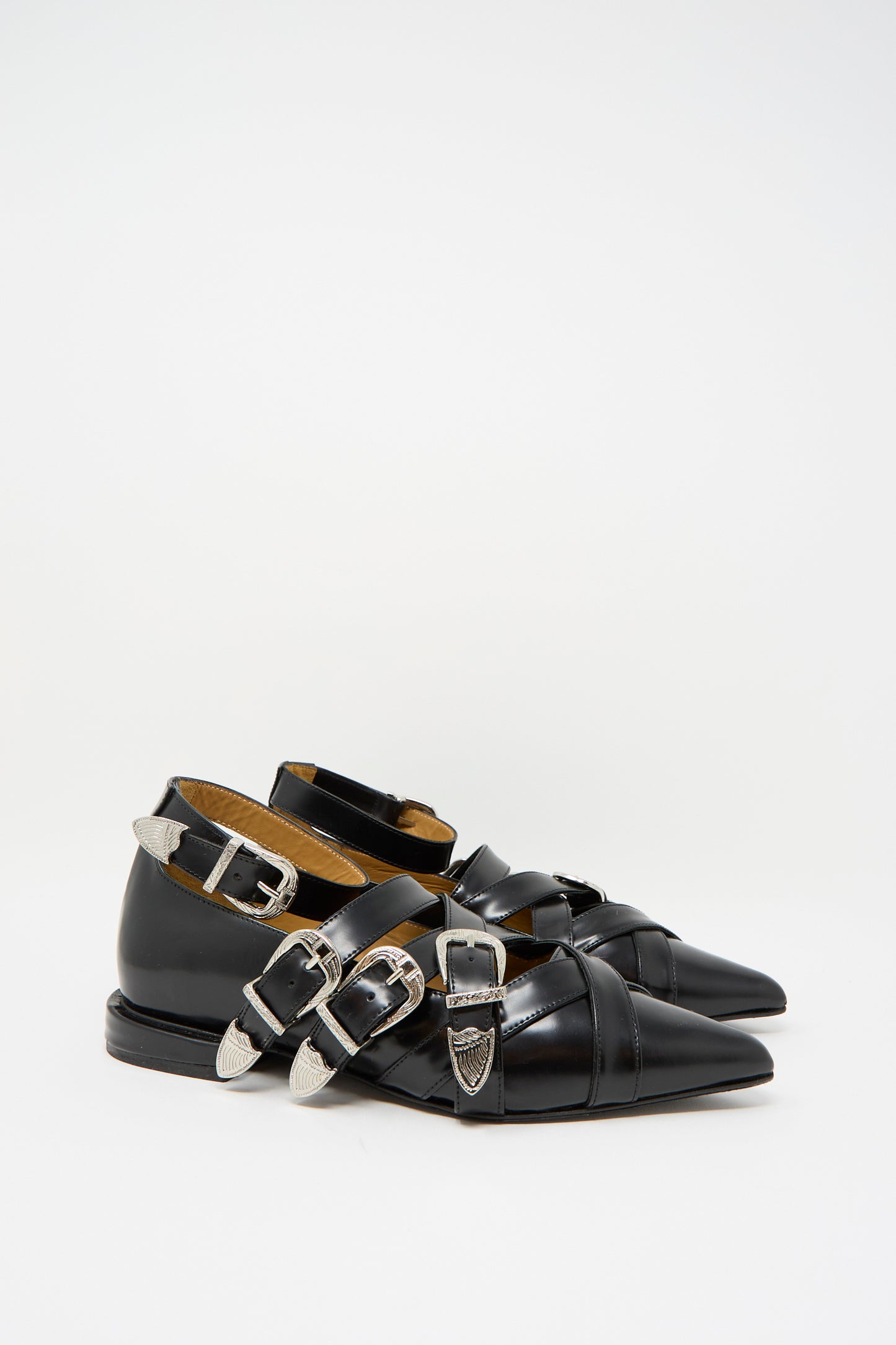 TOGA ARCHIVES presents the Leather Polido Flat in Black, featuring a pointed toe, multiple silver buckles, and an elegant ankle strap,  on a plain background.