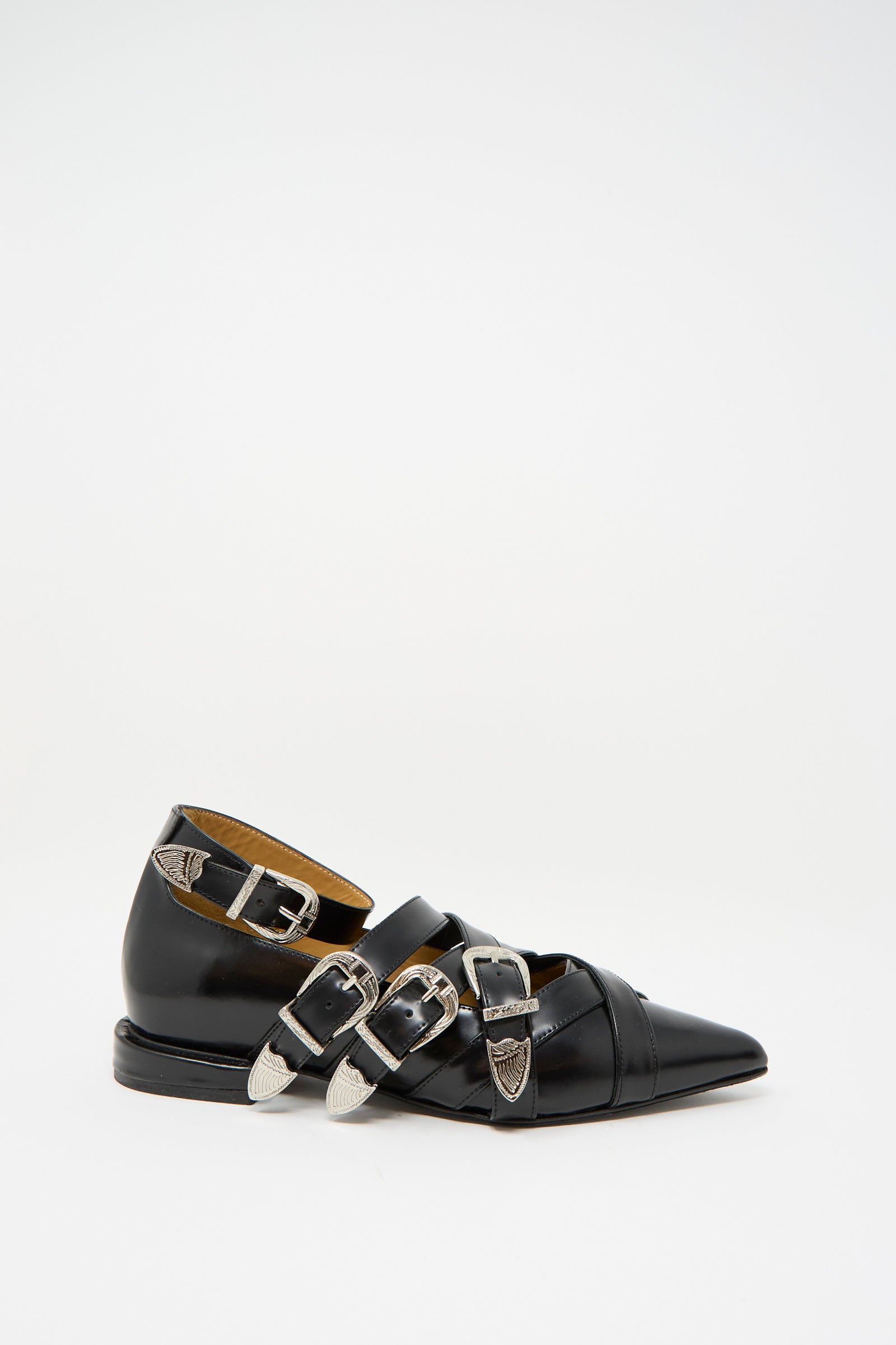 The TOGA ARCHIVES Leather Polido Flat in Black, featuring multiple silver buckles and ankle straps, is displayed on a light background.