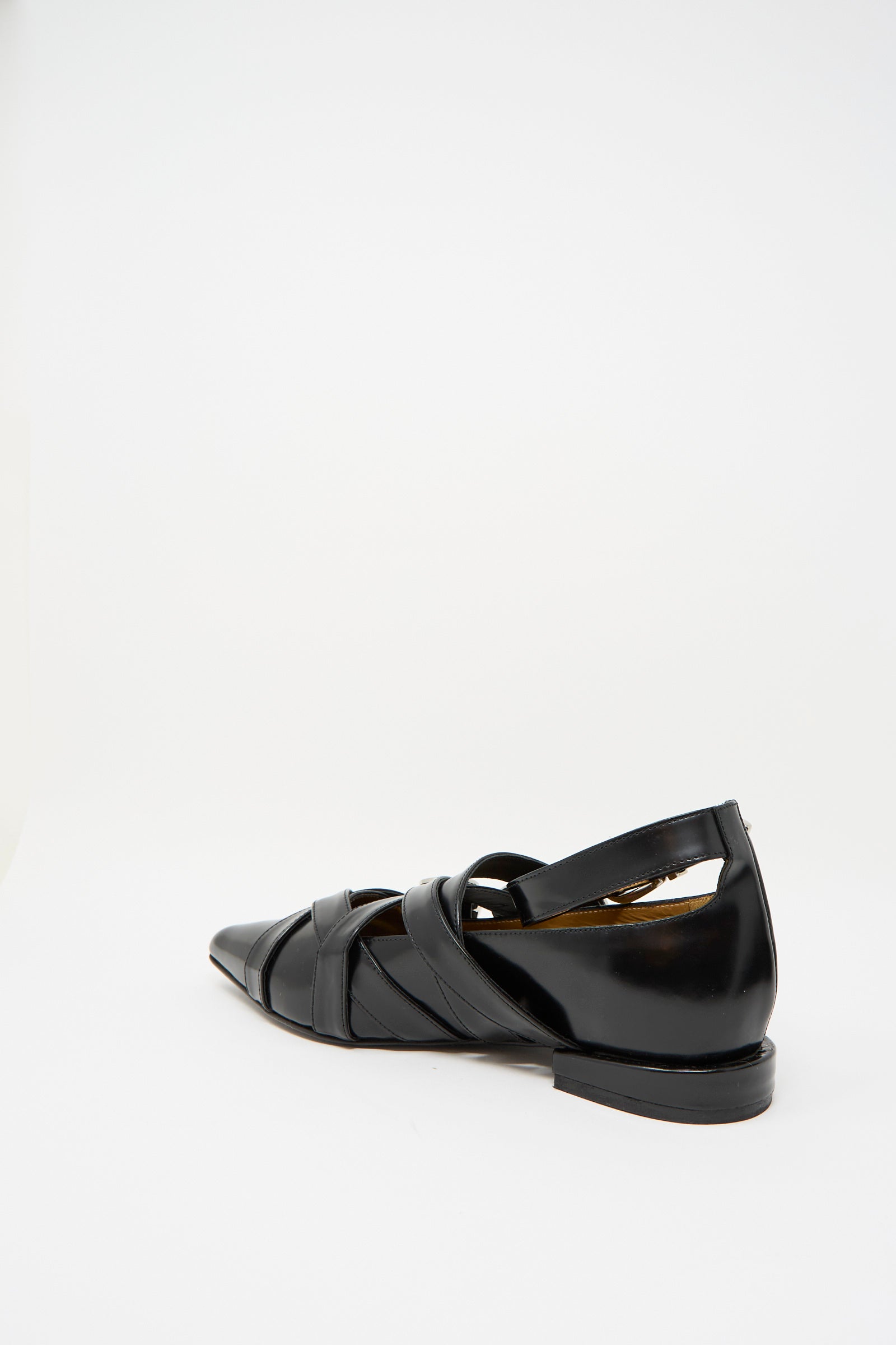 The Leather Polido Flat in Black by TOGA ARCHIVES features a pointed toe, crisscross straps, and an ankle strap, viewed from the rear.