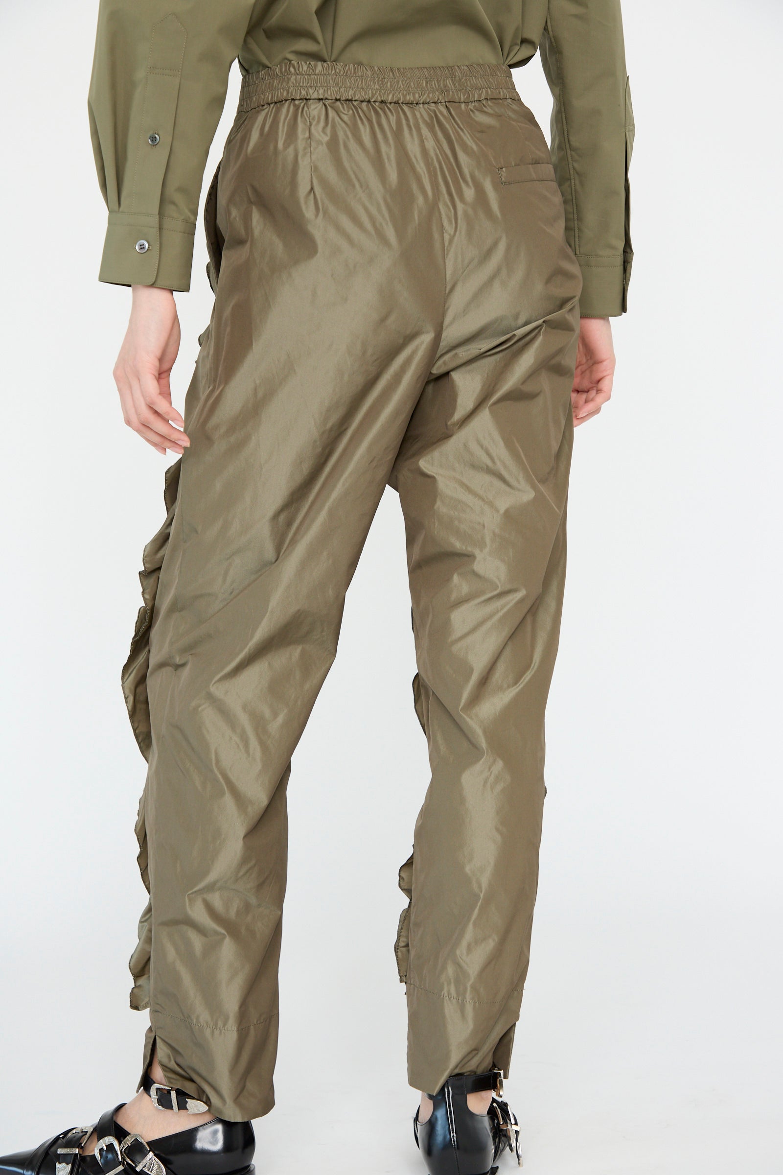 The model is wearing TOGA ARCHIVES' Memory Taffeta Pant in khaki with a matching shirt, paired with black shoes, all shown from the back against a plain background.