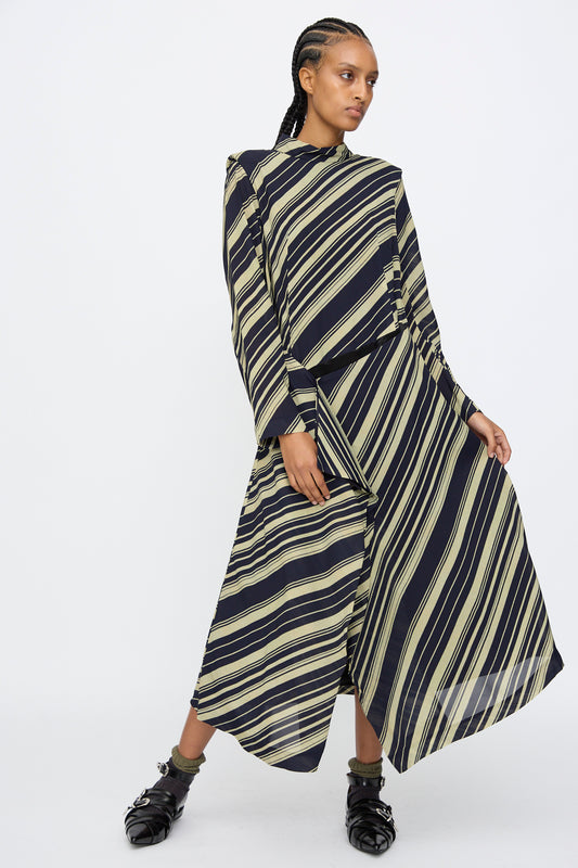 A person wearing the TOGA ARCHIVES Rayon Print Dress in Navy stands against a plain white background, posing with one leg slightly bent.