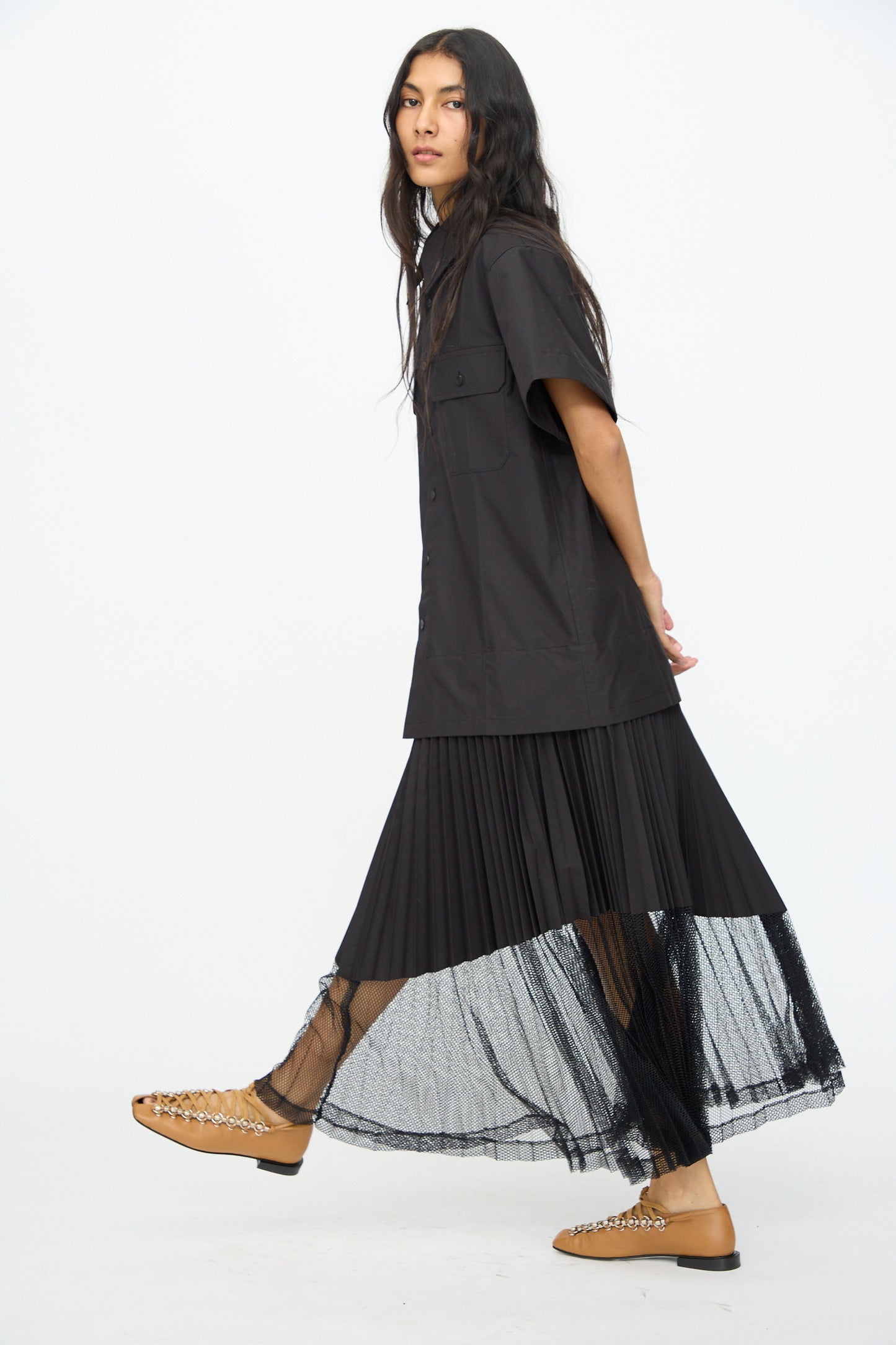 A person walks against a plain white background wearing the TOGA ARCHIVES Typewriter Mesh Dress in Black.