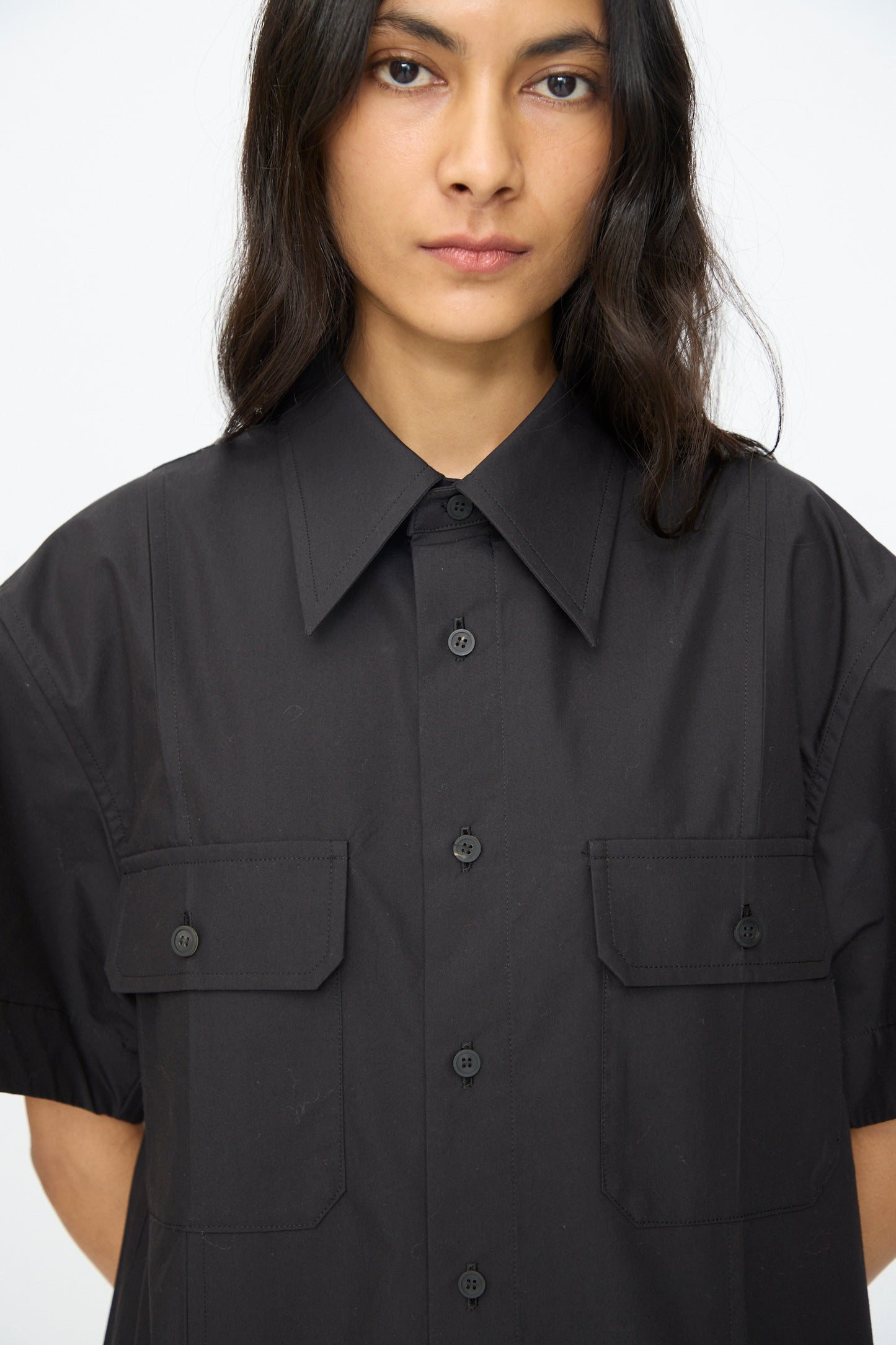 A person with long, dark hair wearing the TOGA ARCHIVES Typewriter Mesh Dress in Black, facing forward against a plain background.