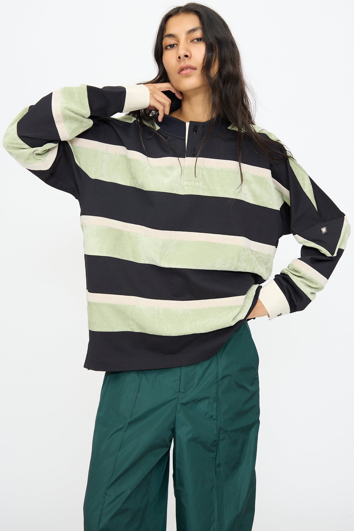 A person wearing the TOGA ARCHIVES Velvet Border Jersey Long Sleeve in light green with green pants, standing against a plain white background.