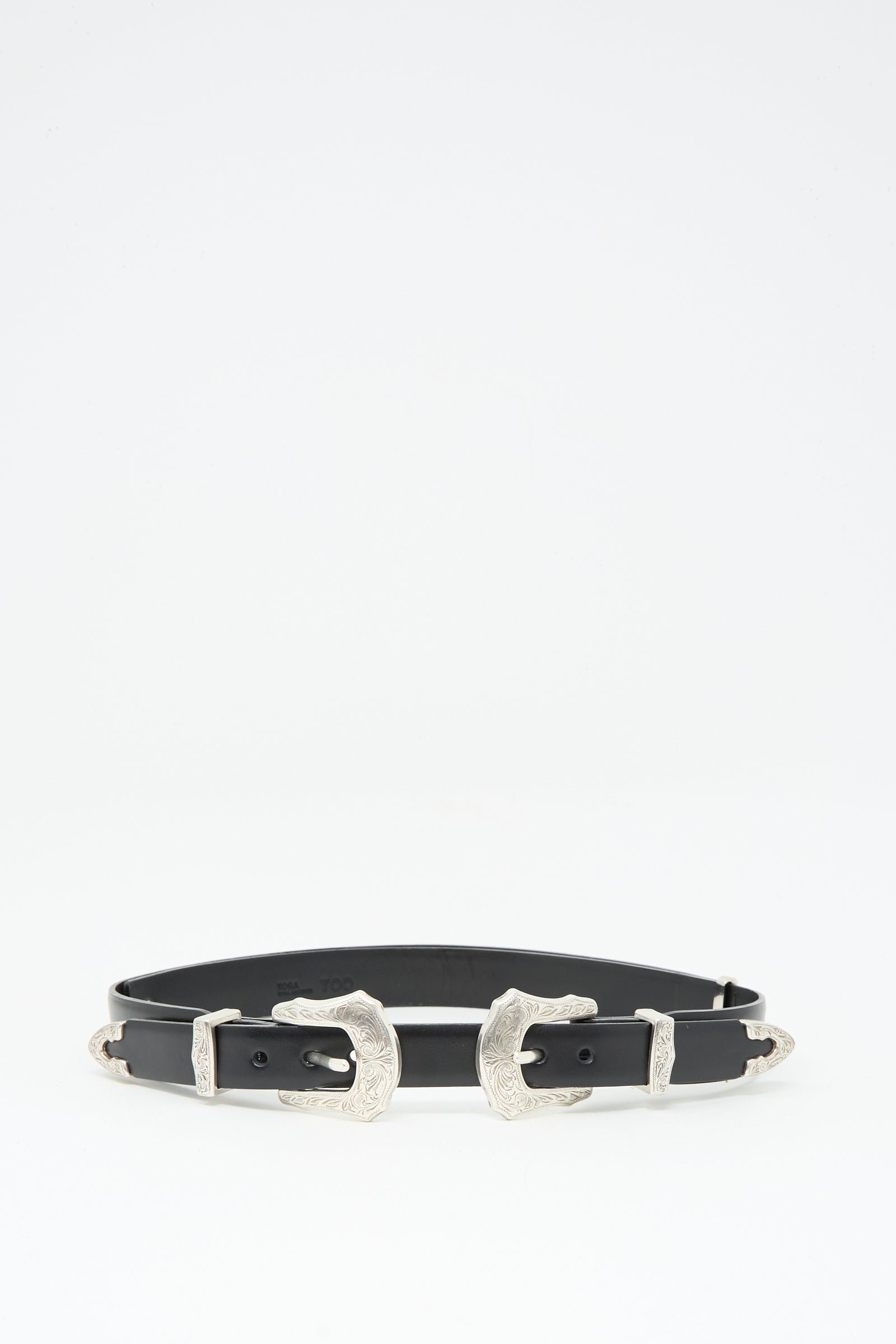 The TOGA ARCHIVES Double Buckle Belt in Black is crafted from black cowhide leather with two engraved silver buckles and matching tips, shown against a plain white background.