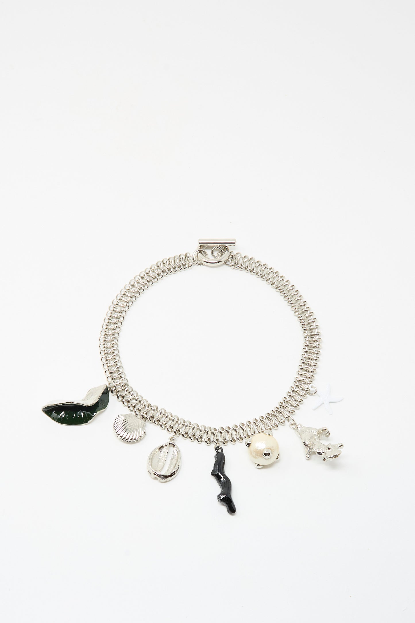 The TOGA ARCHIVES Motif Necklace in Silver features assorted charms—green leaf, seashell, round bead, black twig, small flower, and star—with a secure toggle clasp, displayed on a white background.