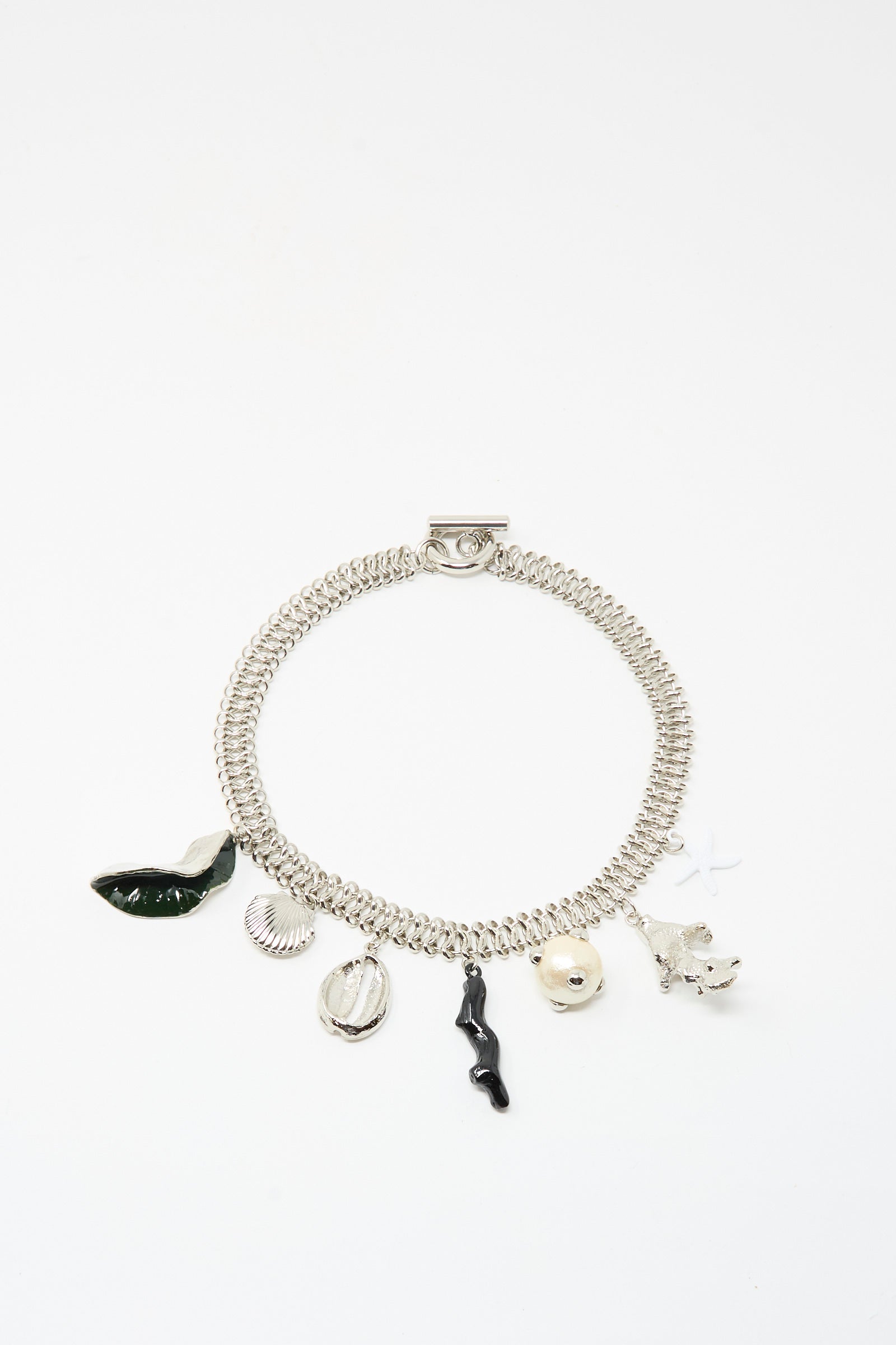 The TOGA ARCHIVES Motif Necklace in Silver features assorted charms—green leaf, seashell, round bead, black twig, small flower, and star—with a secure toggle clasp, displayed on a white background.