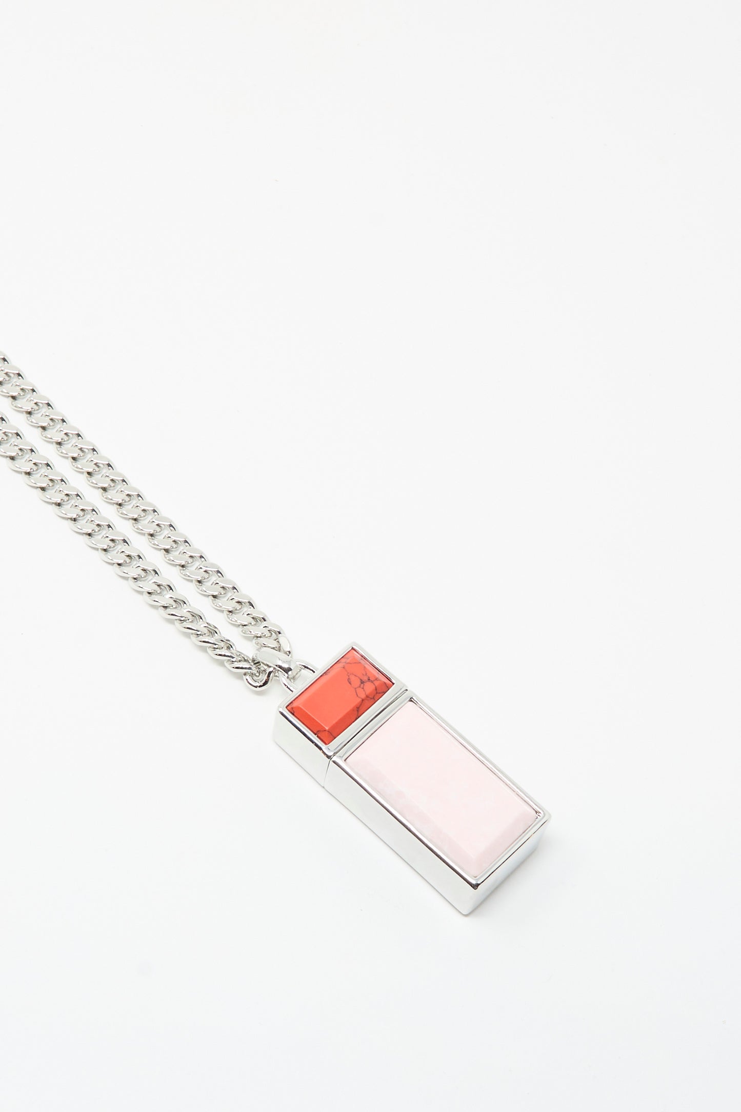 The TOGA ARCHIVES Pill Case Necklace in Light Pink features a silver chain with a rectangular pill case pendant, set with a large pale pink stone and a smaller red stone, crafted in Japan.