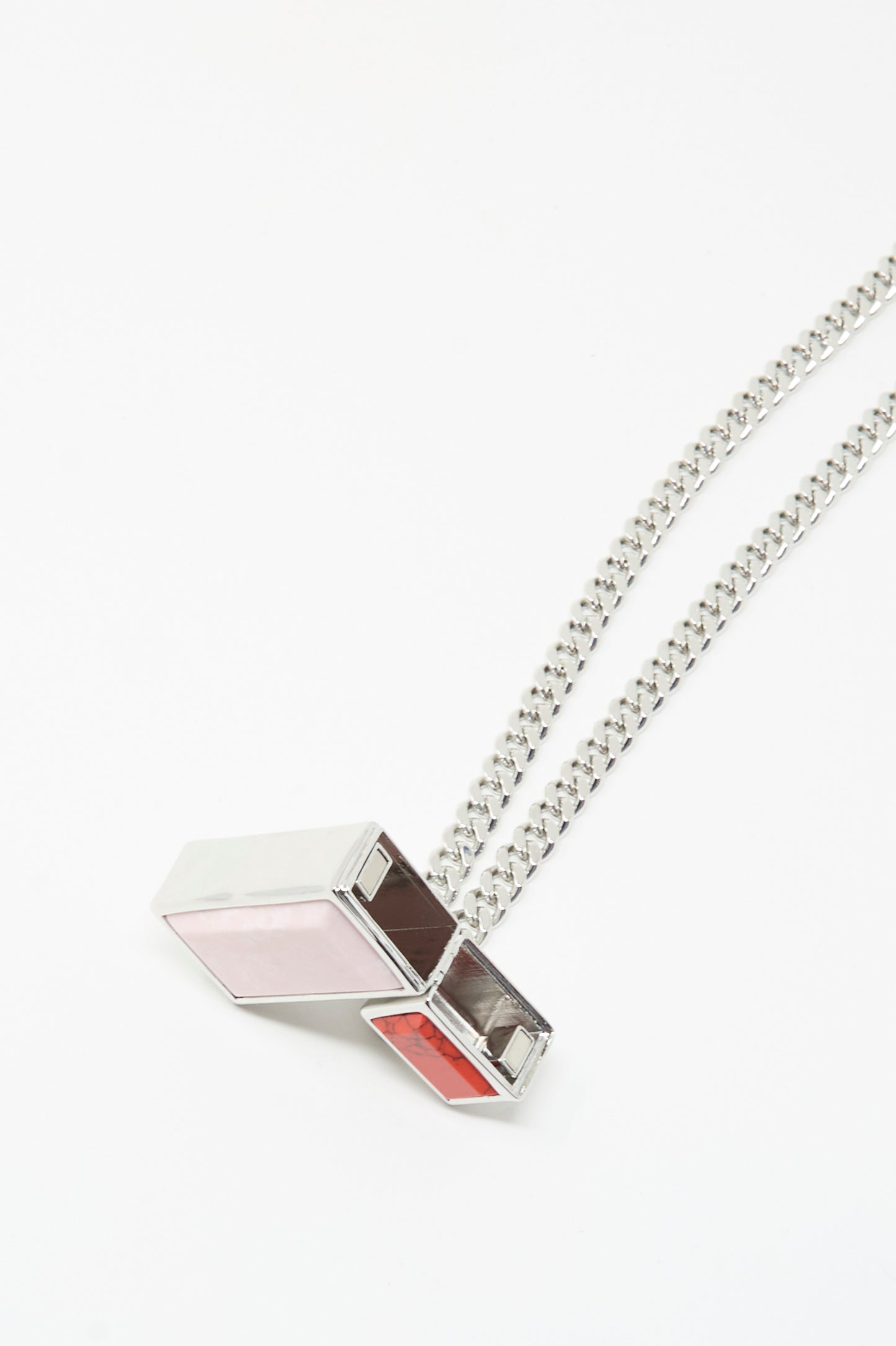 The Pill Case Necklace in Light Pink by TOGA ARCHIVES is a silver chain necklace with a geometric pendant featuring three rectangular stones—pink, brown, and red—in a metal frame. Made in Japan and displayed on a white background.