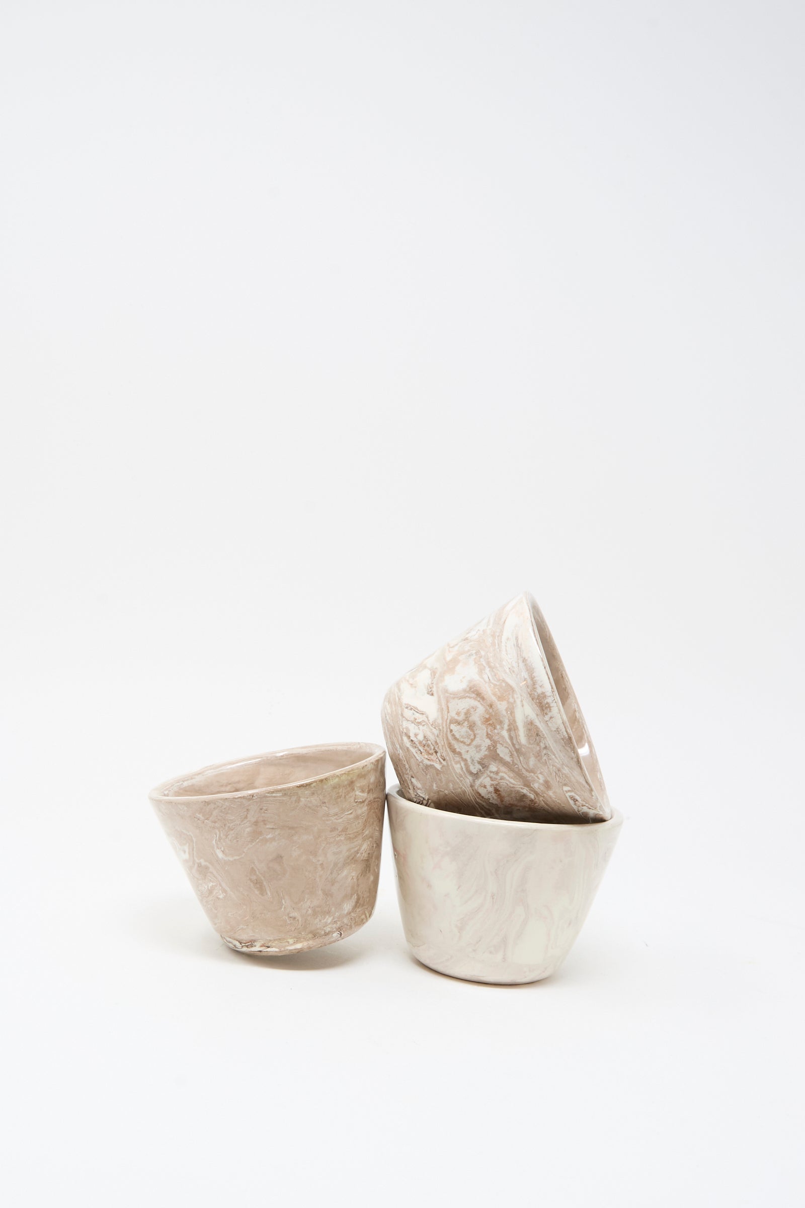 Three Totem Home Ceramic Olive Bowls, featuring a marbleized glaze in neutral tones, are stacked on a white surface against a plain white background.