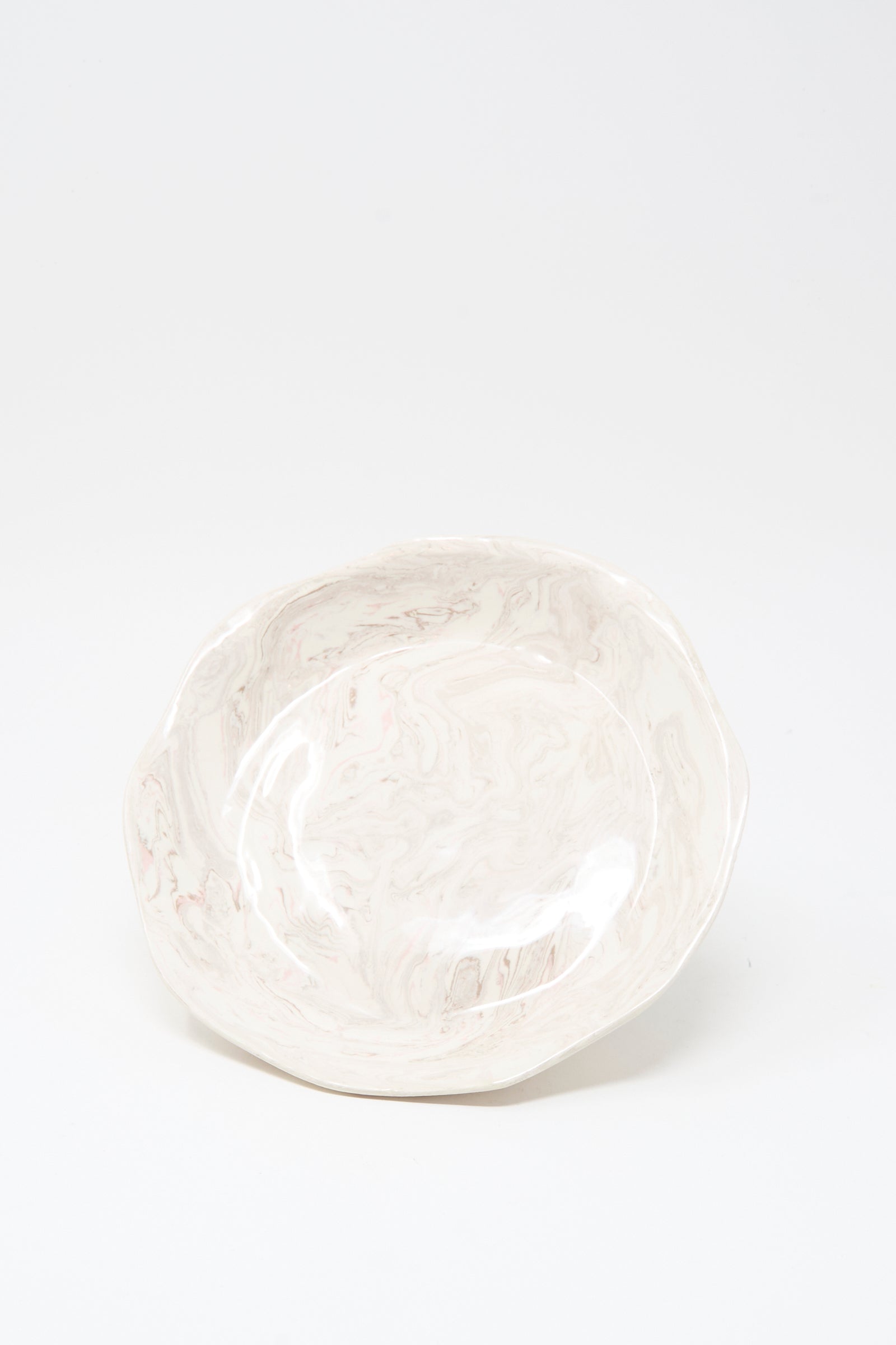 The Wild Rose Shallow Bowl by Totem Home is a handmade ceramic bowl featuring a marbleized pink glaze, crafted in Portugal and shown on a plain white background.