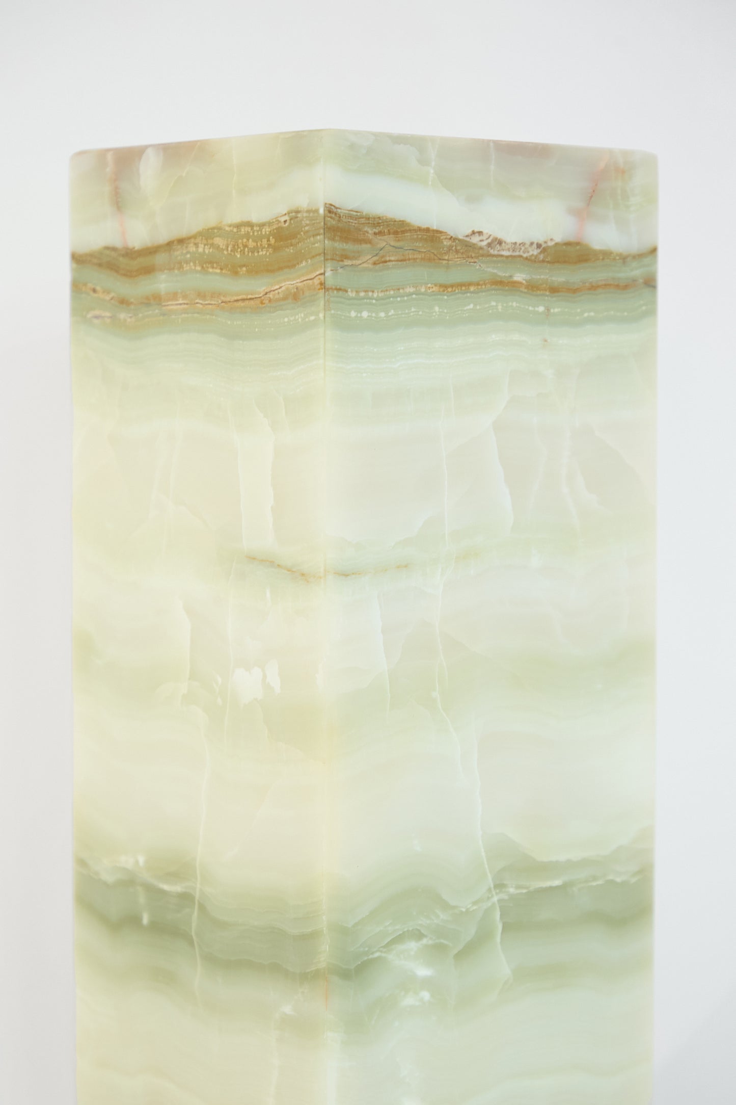 A close-up of a Travel Find Green Onyx Lamp, showcasing its rectangular solid form with horizontal layers in shades of green, white, and brown, set against a plain white background.