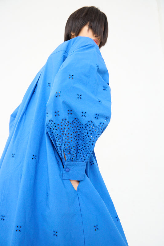Woman in a Ulla Johnson Adette Dress in Cobalt with eyelet design details covering her face from the camera.