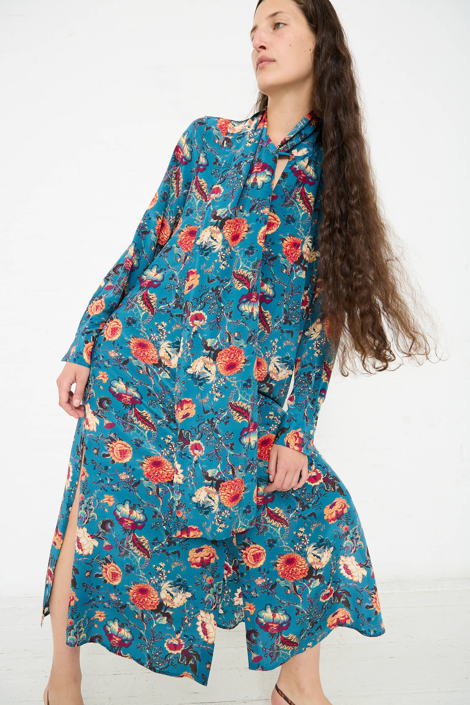 A person with long brown hair is wearing the Ulla Johnson Anisa Dress in Bluette and looking off to the side.