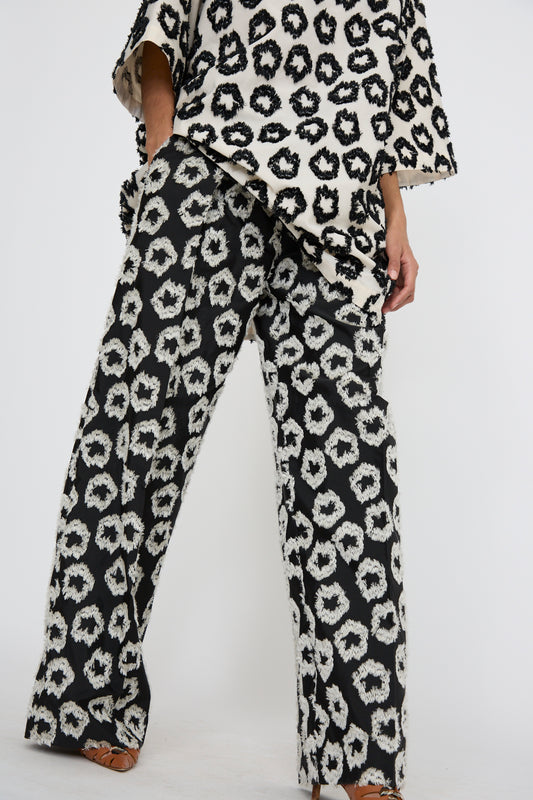 A person is dressed in Ulla Johnson's Cai Pant in Eclipse, showcasing a matching black and white print crafted from an Italian cotton/linen blend, against a white background. 