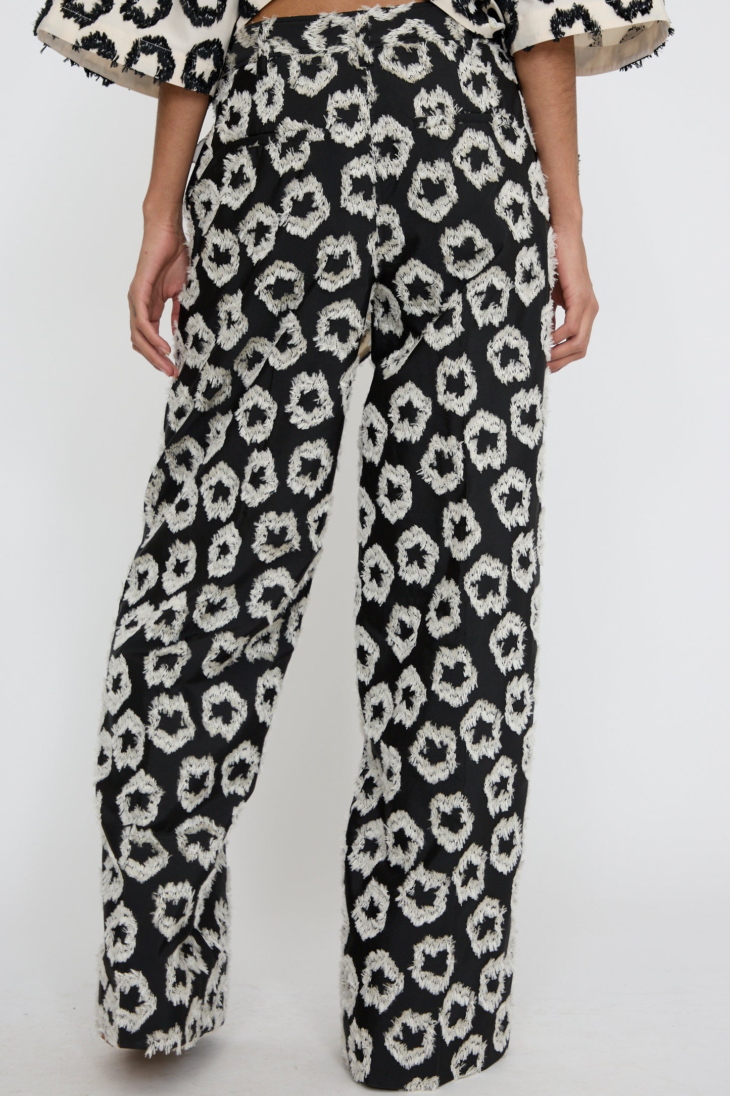 A person is wearing the Cai Pant in Eclipse by Ulla Johnson, featuring a relaxed fit with a black and white abstract pattern made from an Italian cotton/linen blend, standing against a plain background.