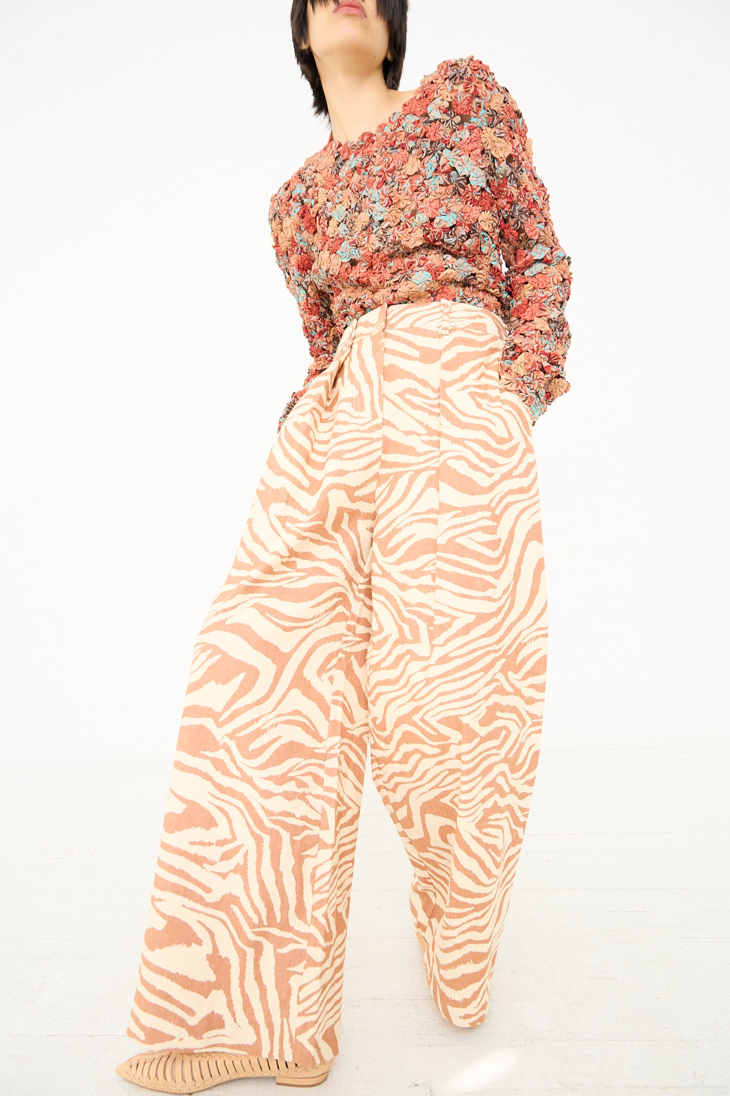 Sentence with replaced product: A person posing in Ulla Johnson's Cai Pant in Gazelle and a floral blouse against a white background.