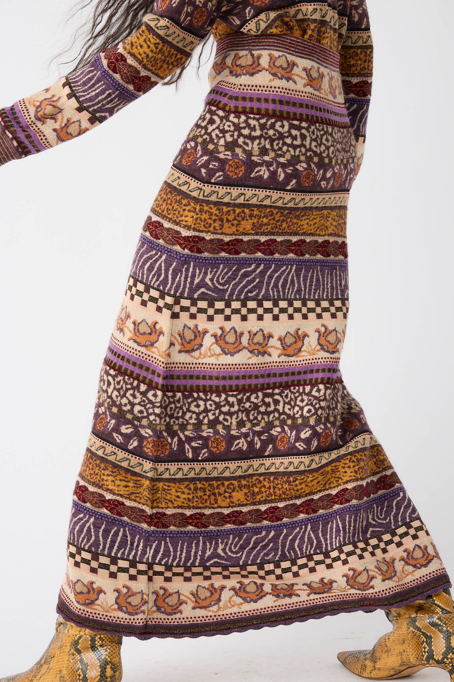 A person wearing the Ulla Johnson Helene Skirt in Woodland, featuring Fair Isle motifs in various colors and designs, paired with yellow snake-print boots. The background is plain white.