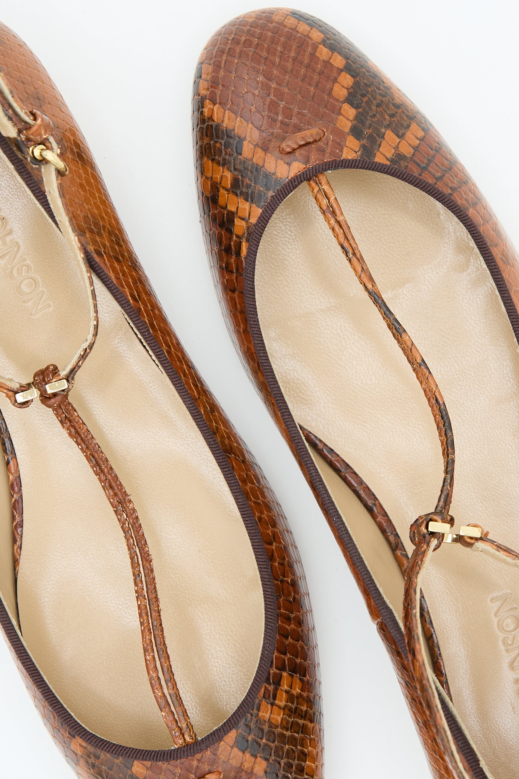 A pair of Ulla Johnson's Mary Jane in Rust Copper, featuring brown animal print leather flats with gold buckles, beige insoles, and an adjustable ankle strap.