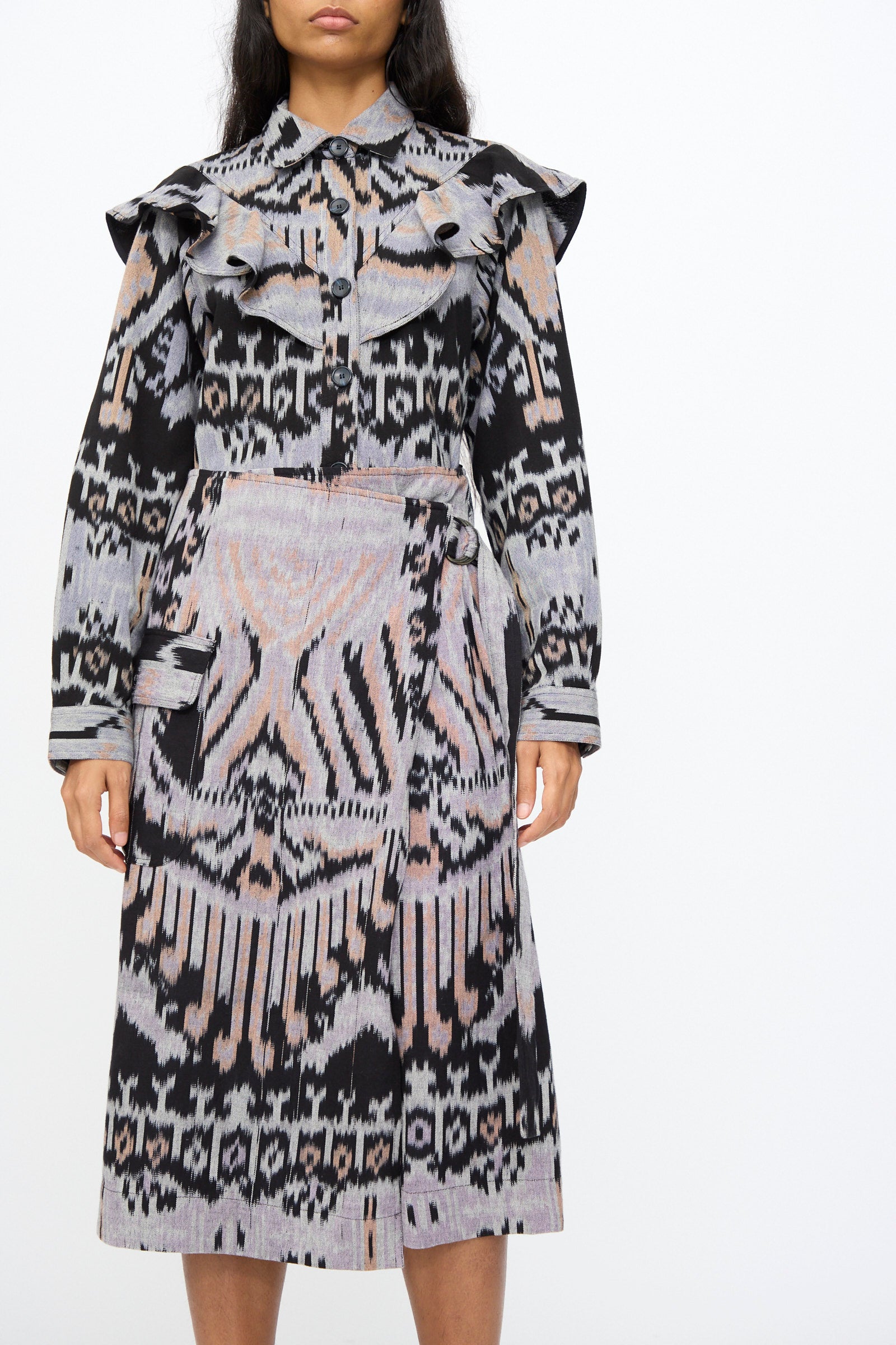 A woman wearing the Ulla Johnson Mila Pencil Skirt in Tigereye, featuring geometric black, gray, and beige ikat motifs.