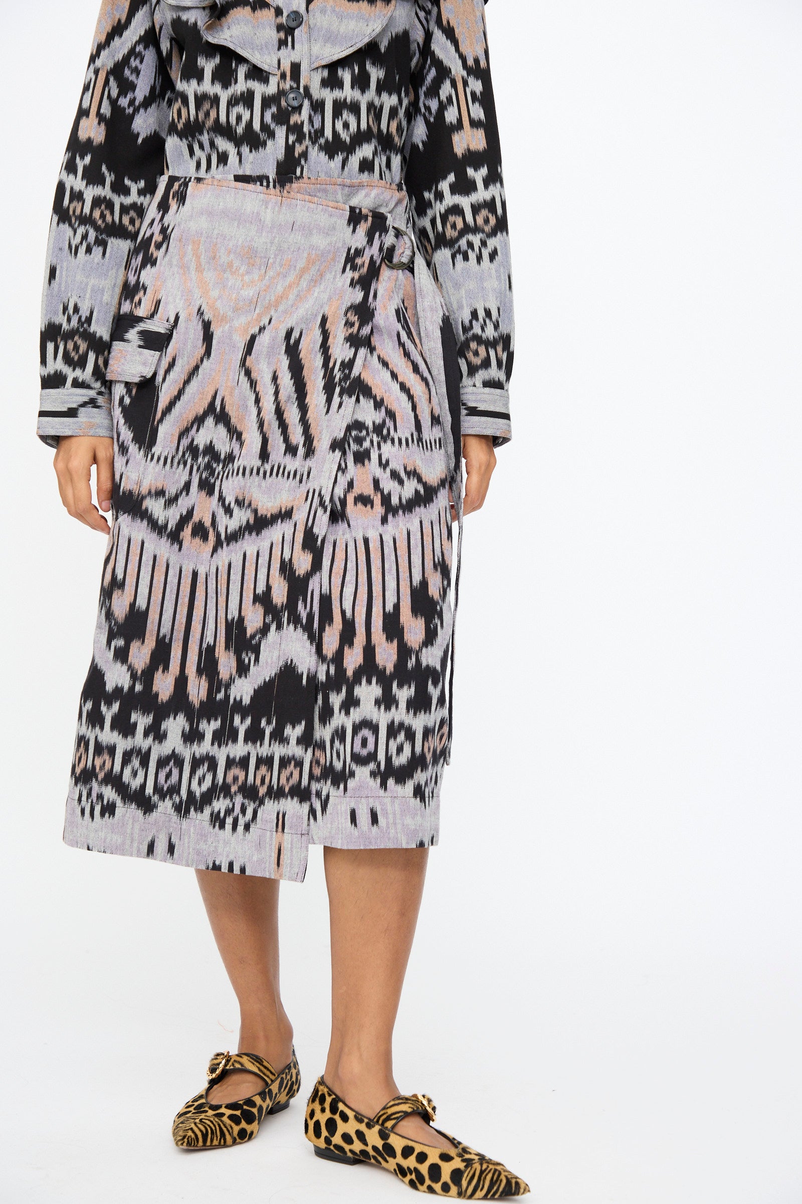 A person wearing the Ulla Johnson Mila Pencil Skirt in Tigereye paired with leopard-print flats. The person's face is not visible.