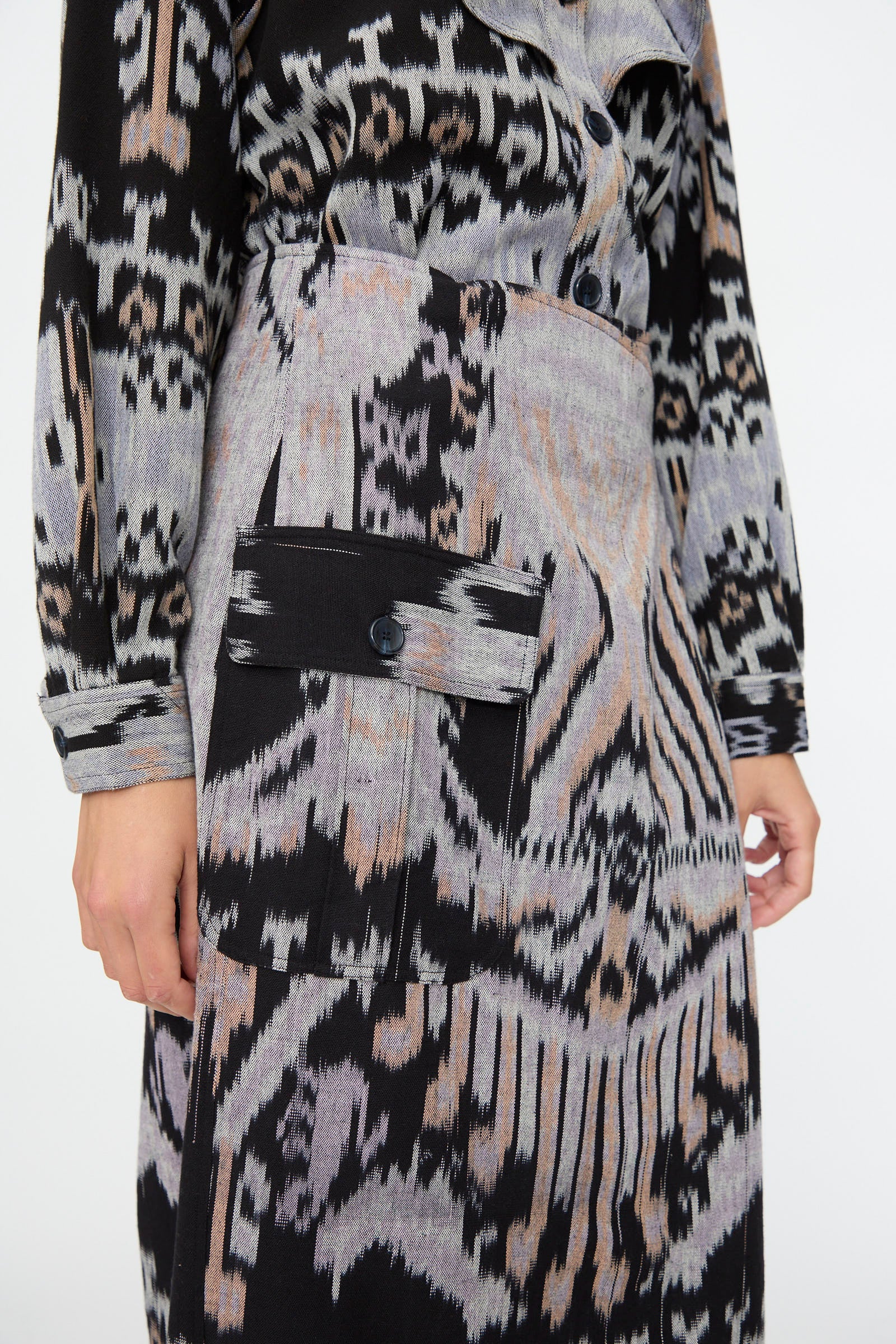 A person wearing the Mila Pencil Skirt in Tigereye by Ulla Johnson, featuring black, gray, and beige abstract patterns and a large buttoned pocket.