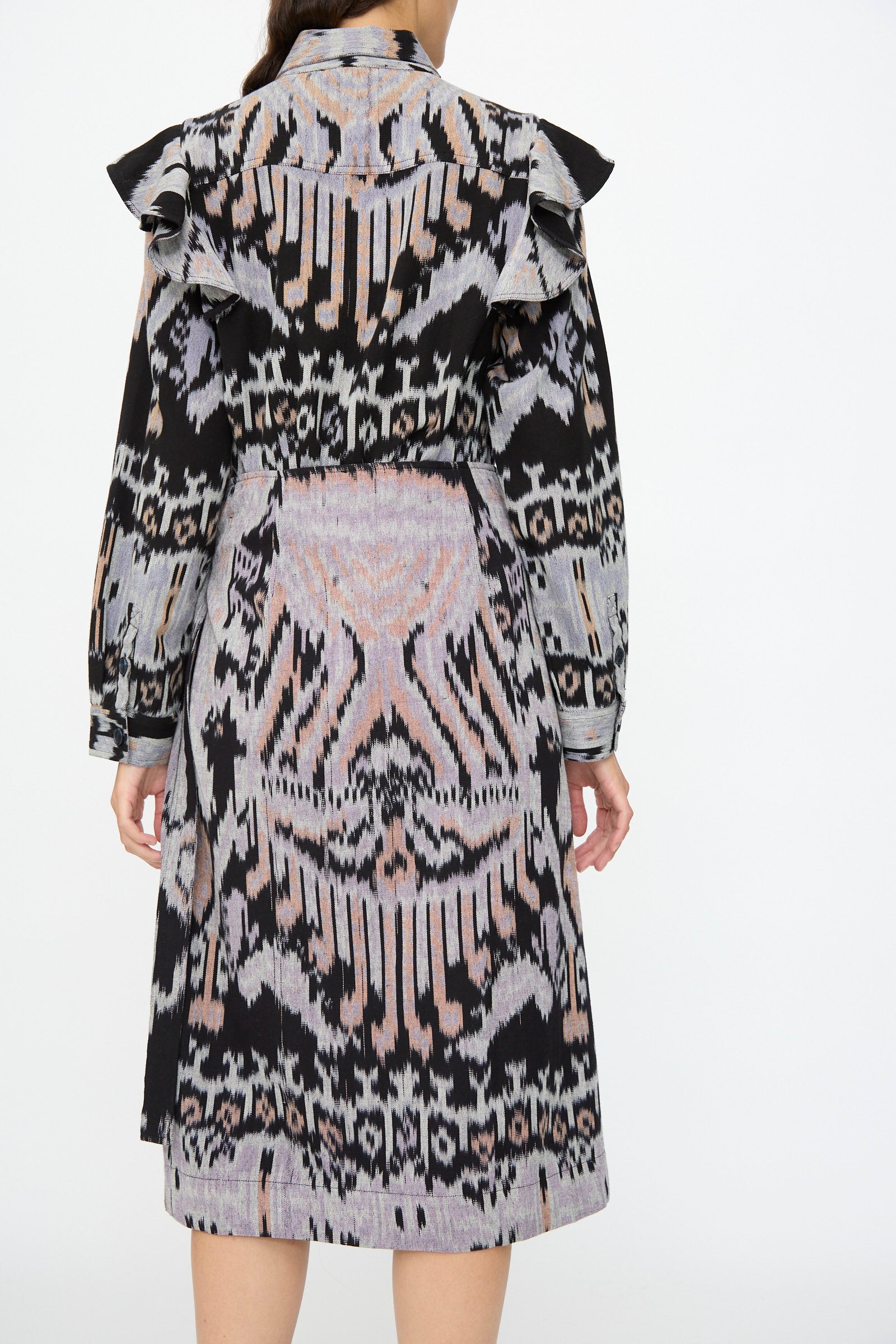 A person is shown from the back wearing the Ulla Johnson Mila Pencil Skirt in Tigereye, featuring a black, gray, and pink abstract ikat-inspired pattern.