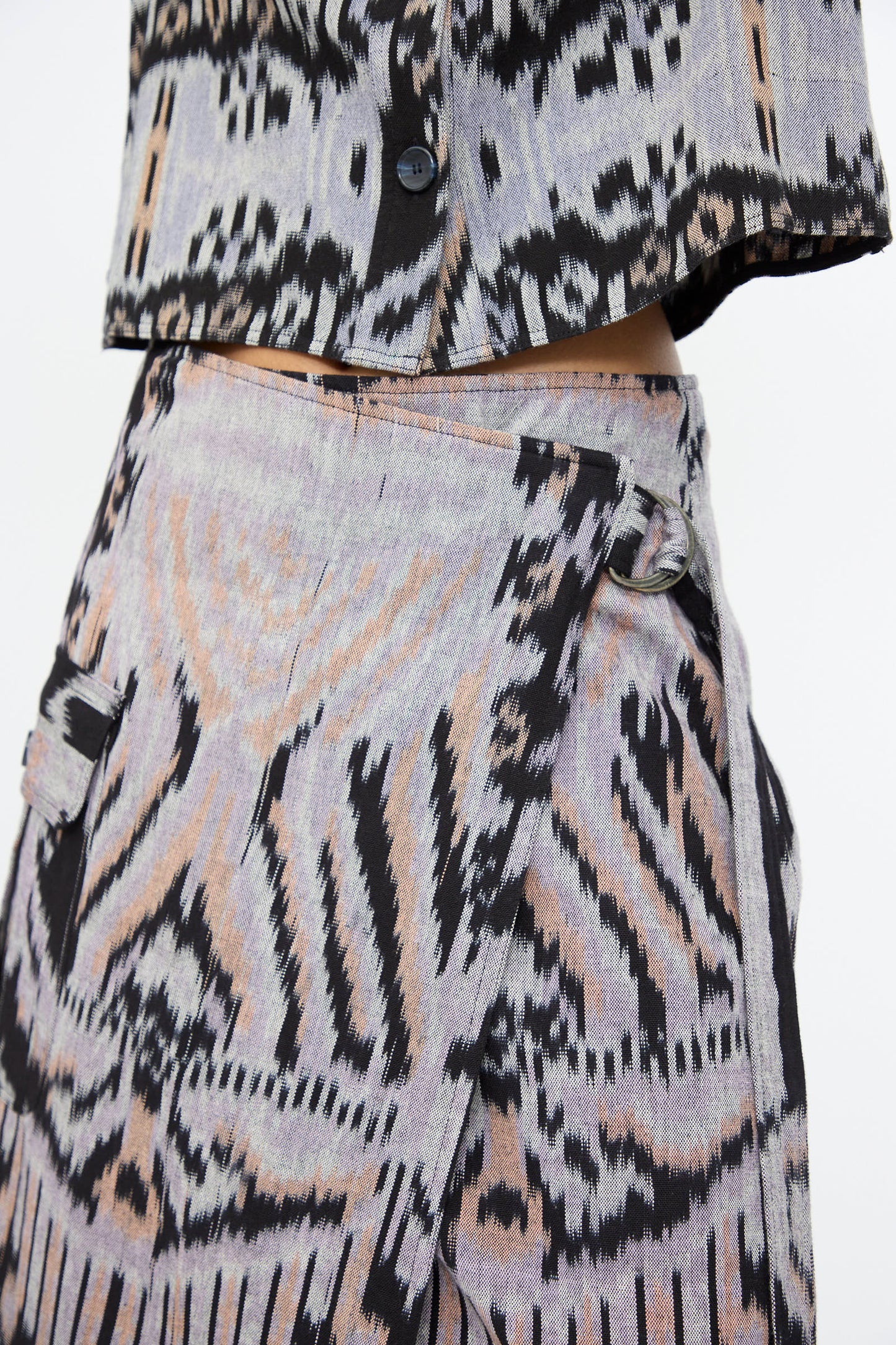 Close-up of a person wearing the Mila Pencil Skirt in Tigereye by Ulla Johnson, featuring hand-loomed cotton with black, grey, and beige abstract ikat motifs.