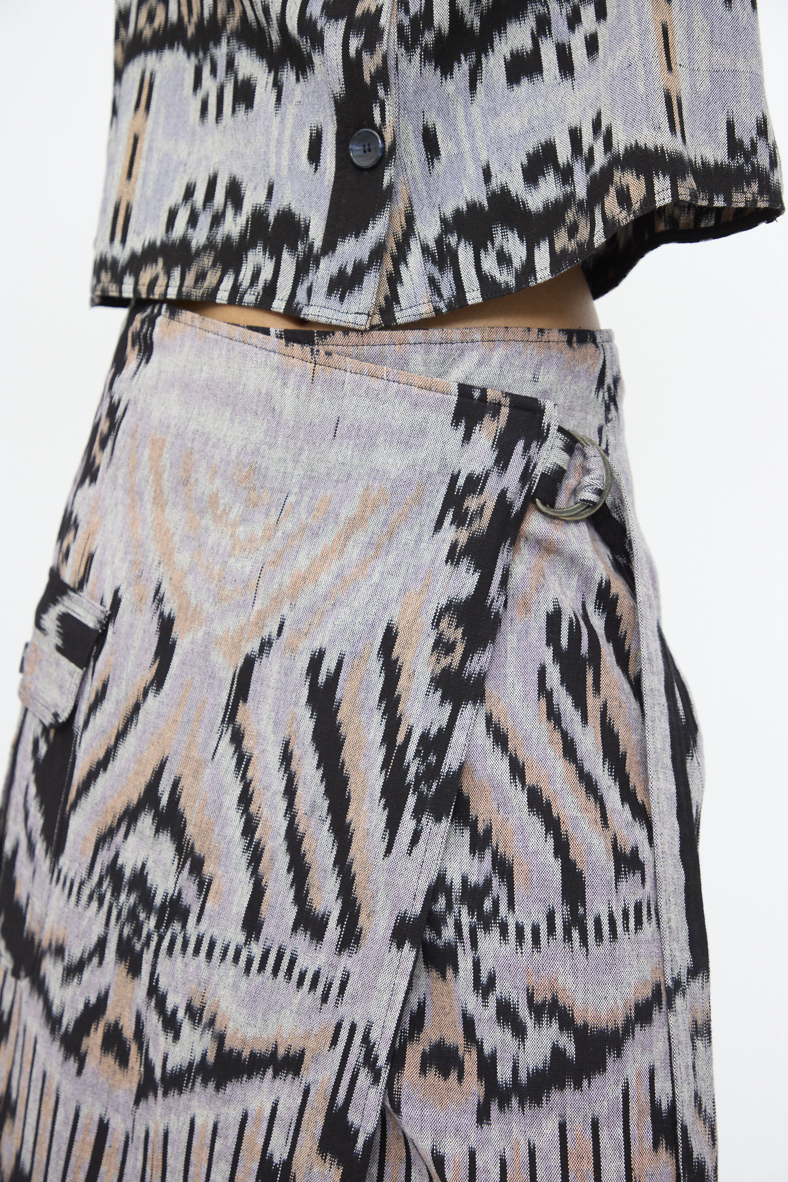 Close-up of a person wearing the Mila Pencil Skirt in Tigereye by Ulla Johnson, featuring hand-loomed cotton with black, grey, and beige abstract ikat motifs.