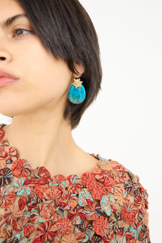 Woman with a bob haircut showcasing a large Mini Spiral Stone Earring in Sonora Sunrise by Ulla Johnson and wearing a floral blouse.