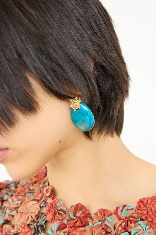 Woman with a bob haircut wearing a Mini Spiral Stone Earring in Sonora Sunrise from Ulla Johnson and a floral garment.