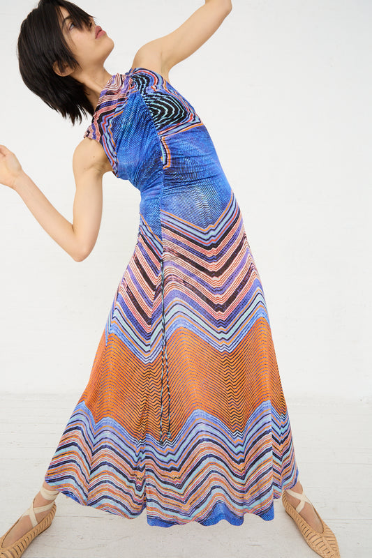 A woman in a flowing multicolored sleeveless Ulla Johnson Natalia Dress in Neptune dancing on a plain background.