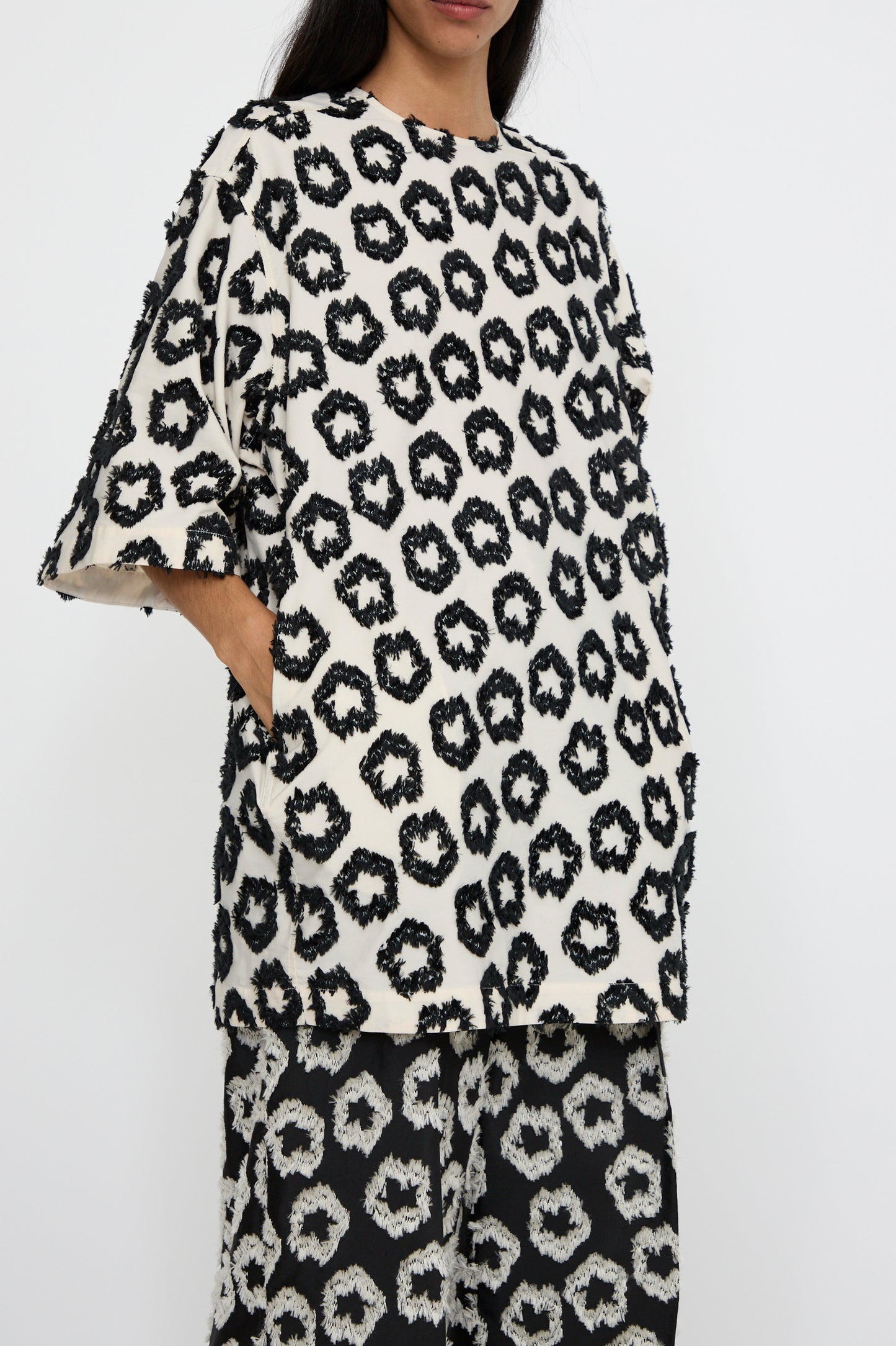 A person is wearing the Remy Tunic in Lunar by Ulla Johnson. The loose-fitting shirt, crafted from a comfortable cotton blend, is paired with matching pants against a white background. 