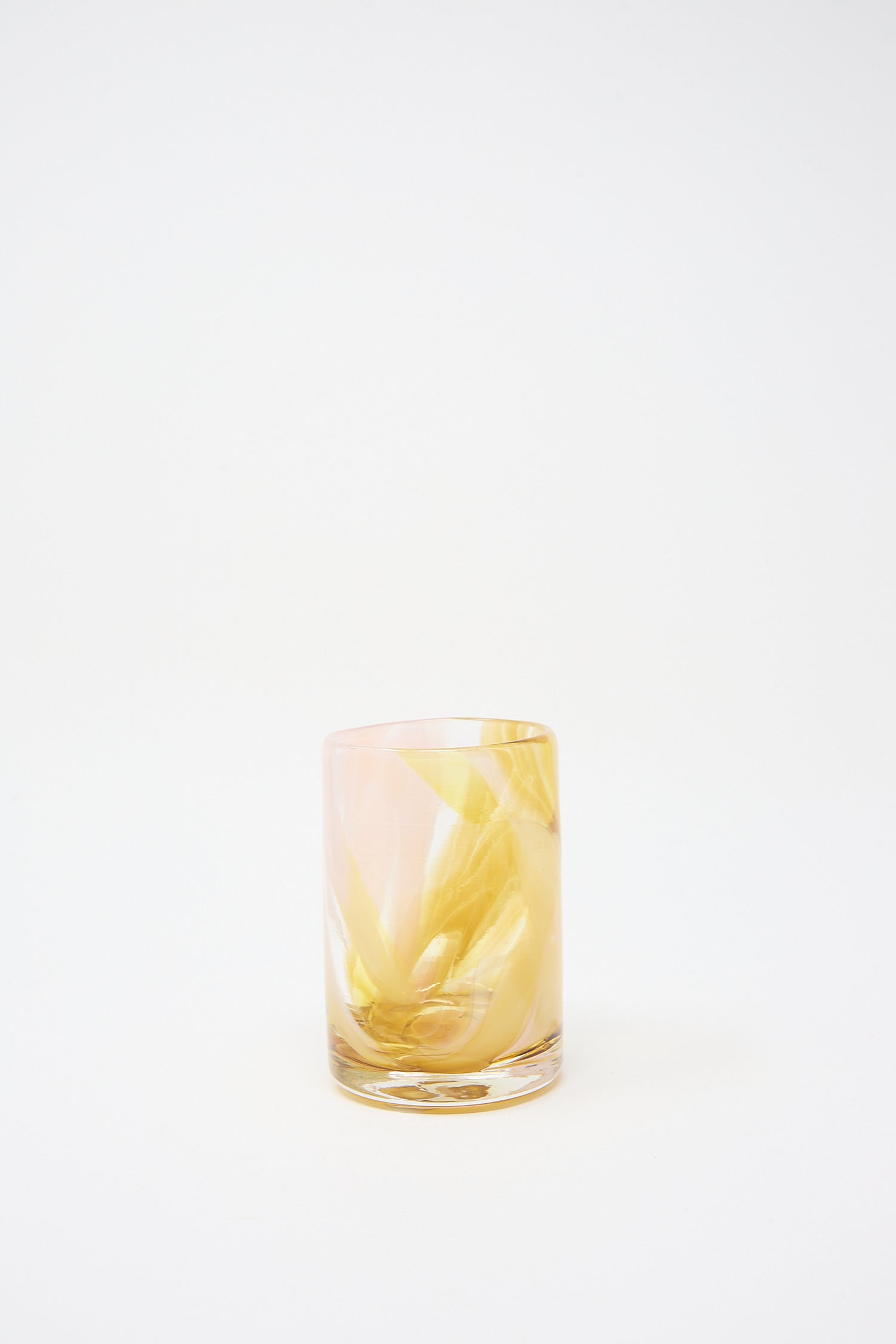 A Frankie Cup by Upstate, hand-blown glass tumbler half-filled with a yellow liquid and ice against a white background.