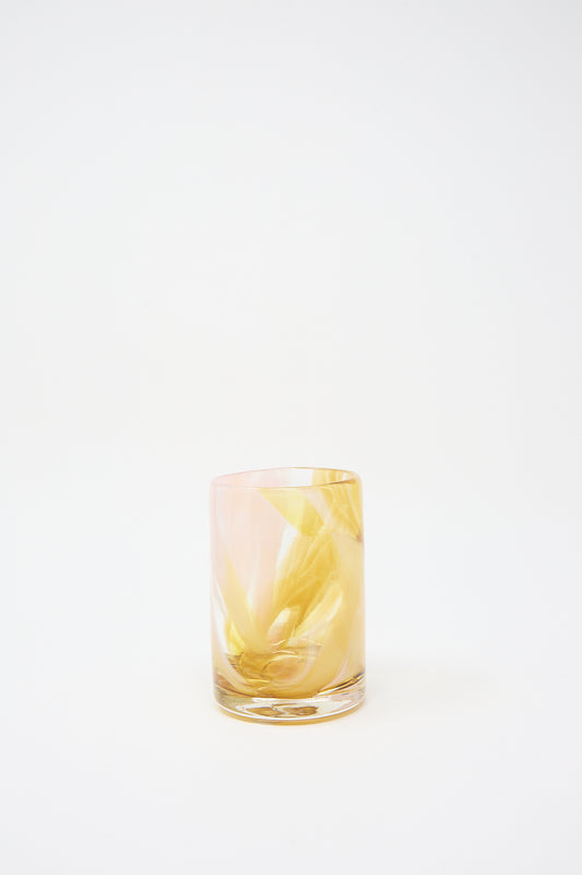 A Frankie Cup by Upstate, hand-blown glass tumbler half-filled with a yellow liquid and ice against a white background.