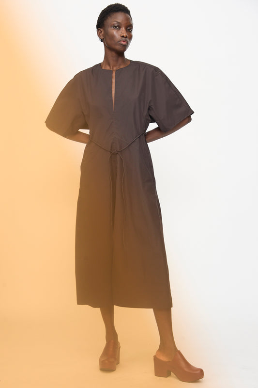 A person stands against a white background wearing the Veronique Leroy Belted Kimono Dress in Choco, styled with brown heeled shoes.