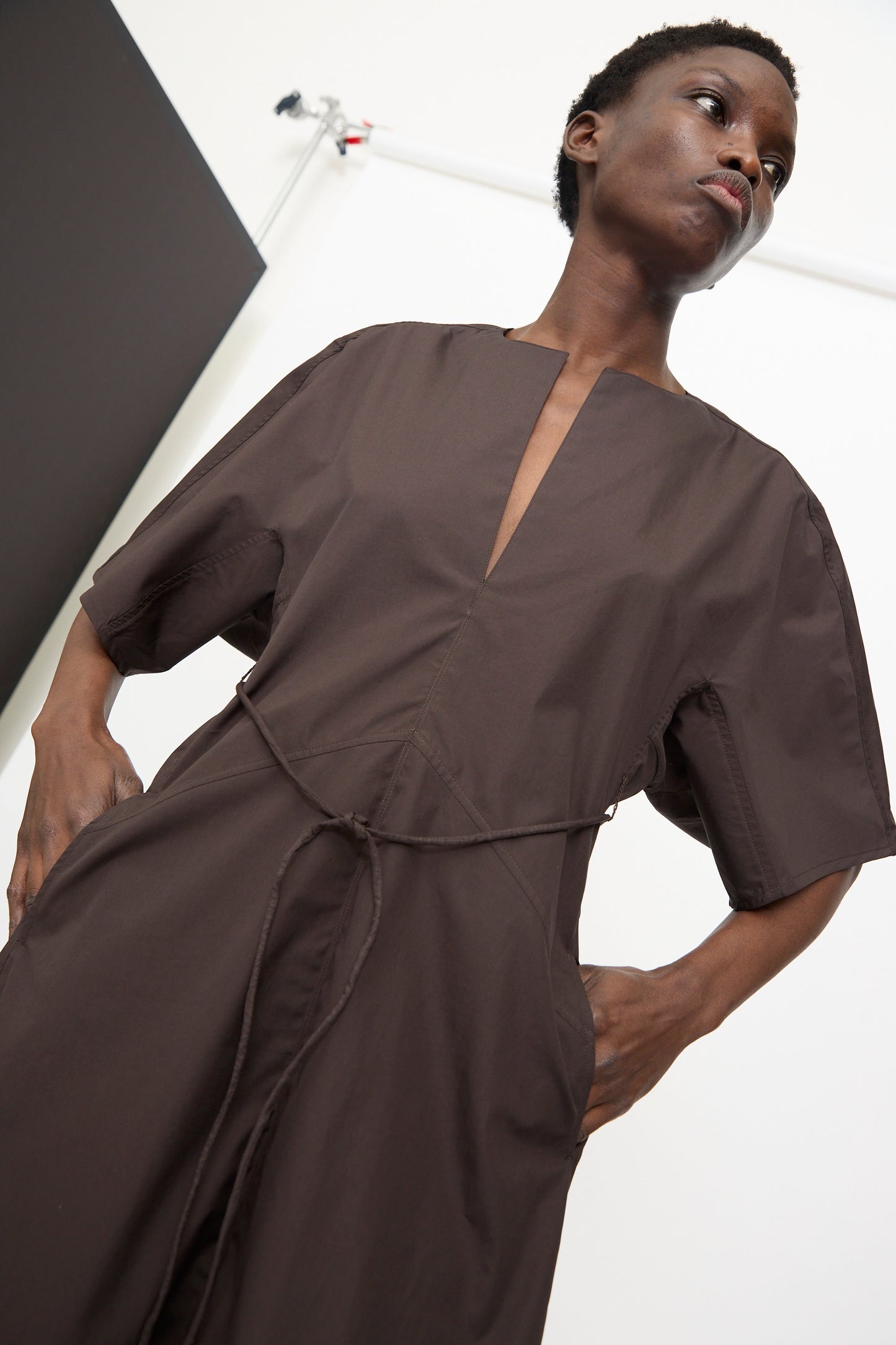 A person wearing the Veronique Leroy Belted Kimono Dress in Choco stands before a light background, looking slightly upward.