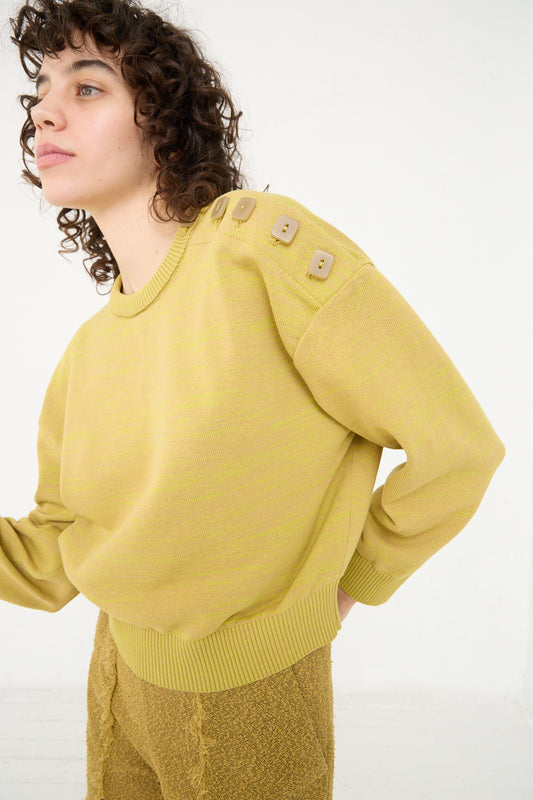 A woman with curly hair wearing a yellow knit Cotton Boxy Sweater in Curry by Veronique Leroy.