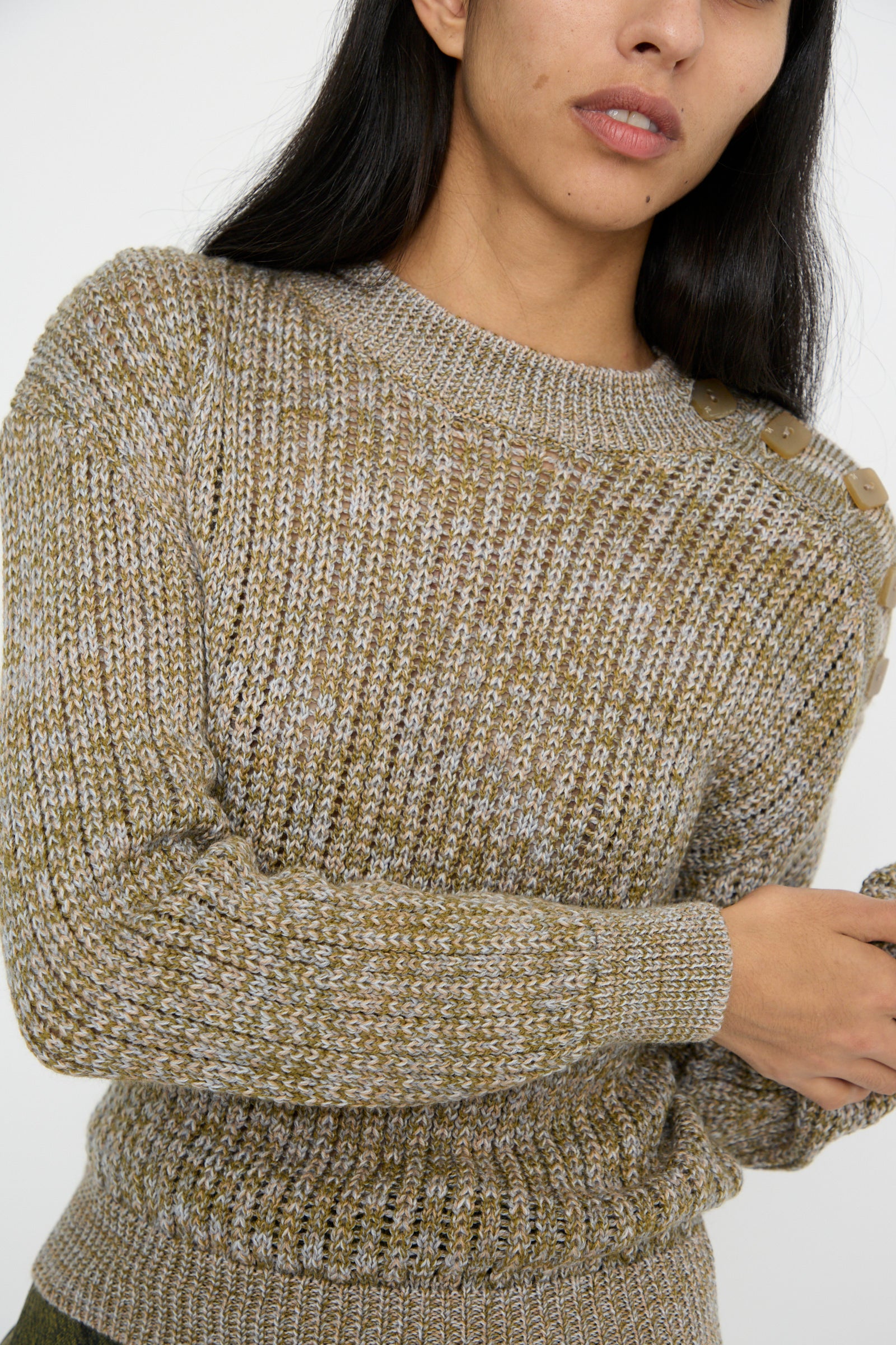 A person wearing the Button Shoulder Sweater in Meadow by Veronique Leroy, styled with a boxy fit and button detail on the shoulder, is standing against a plain background.